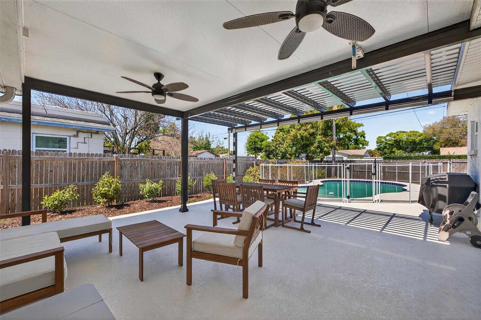 Spacious covered patio and pergola(added in 2021), with ceiling fans, and outdoor seating next to the pool - perfect for relaxing or entertaining.