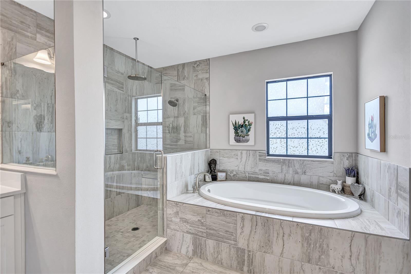 Unwind in a spa-like bathroom featuring a large walk-in shower with a rain shower head, built in bench, and soaking garden tub designed for total relaxation.