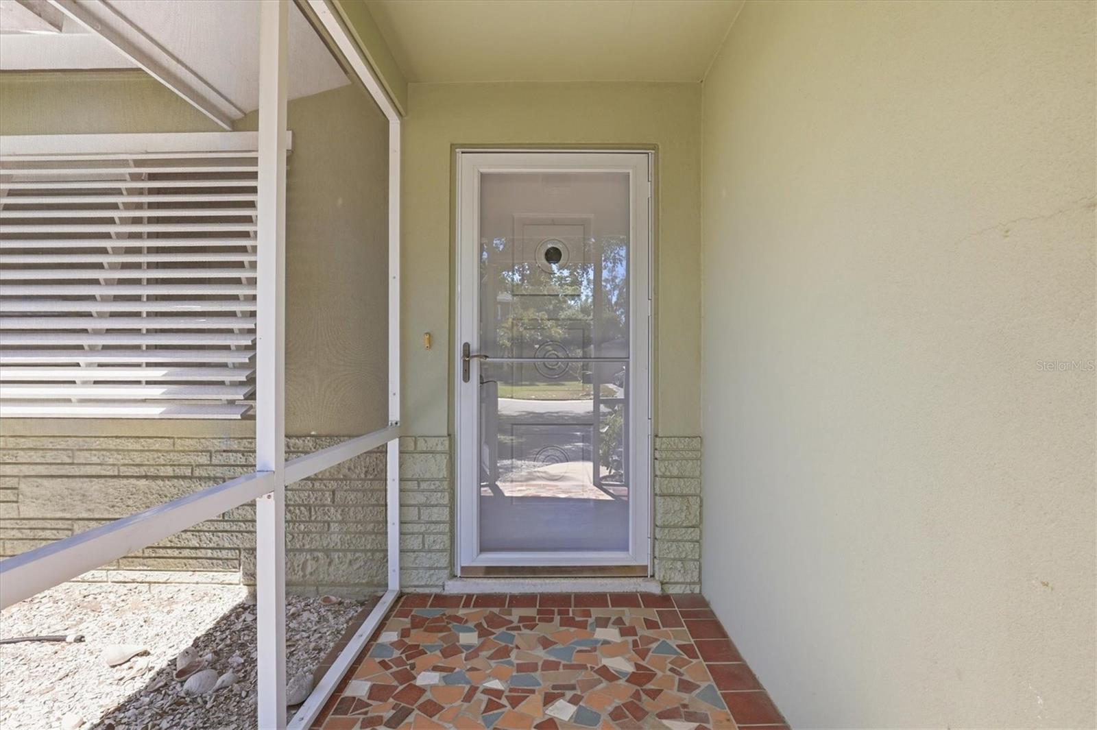 Front screened porched entryway leading into bright, open living spaces