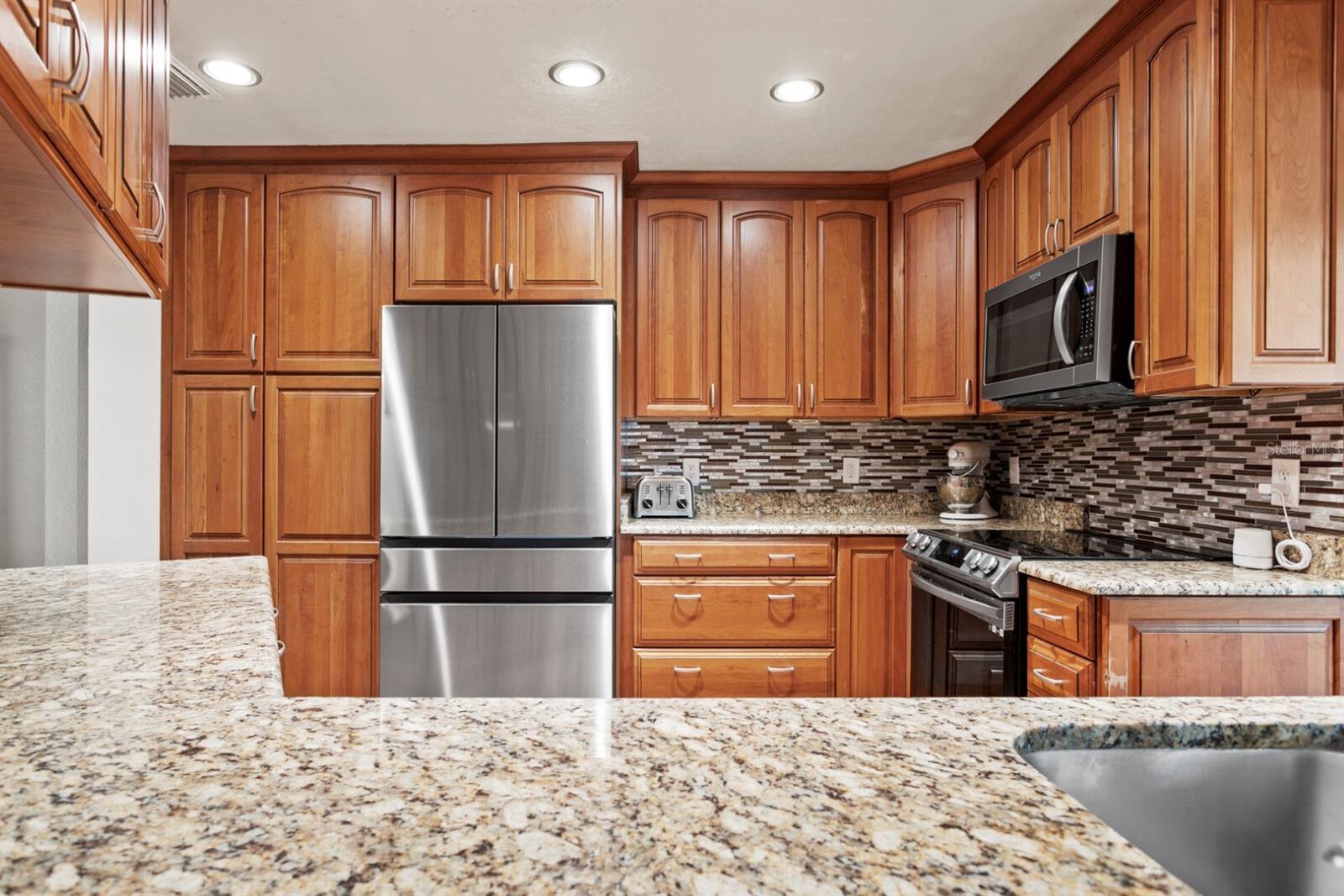 Granite and Cherry Wood Cabinets In Kitchen