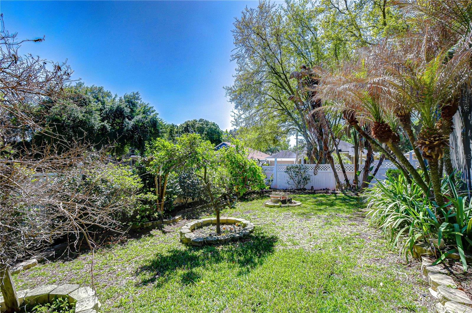 Sunlit paver patio with lush landscaping, privacy fencing, and a screened pool enclosure for outdoor living.