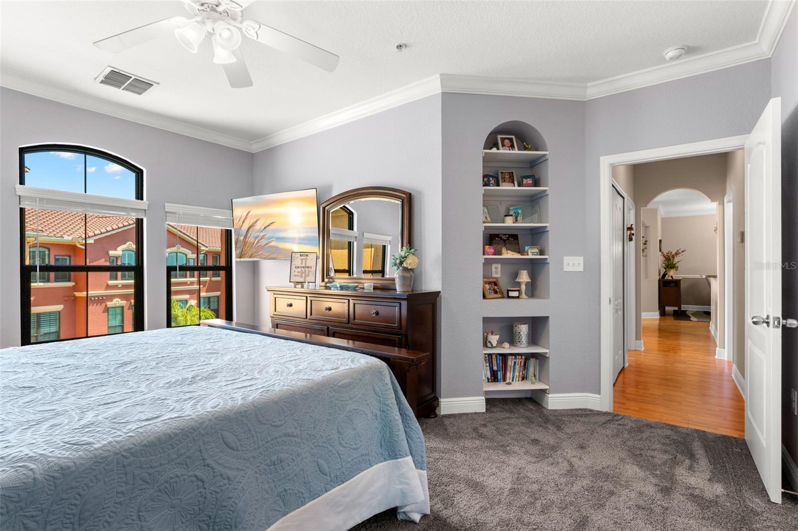 Built-in shelving, plush carpet and crown molding enhance the primary space, offering both style and practical storage.