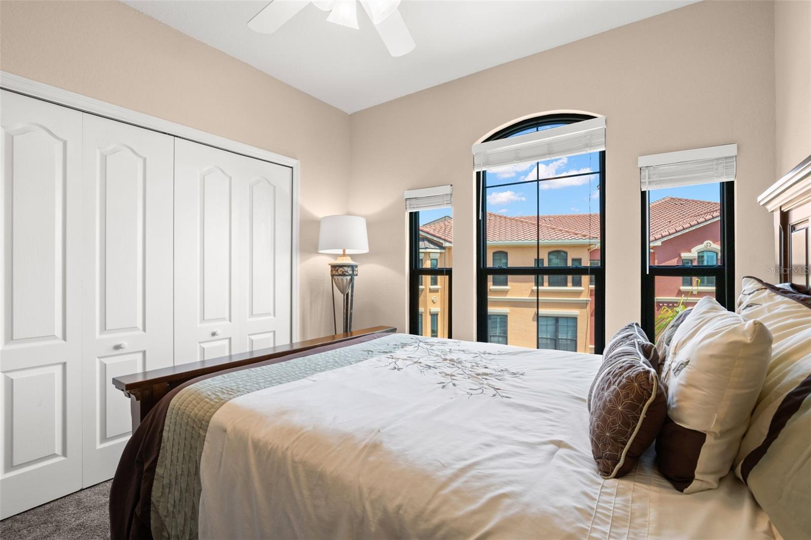 With plush carpeting, a ceiling fan overhead, and arched windows, the second bedroom offers a bright and inviting space.