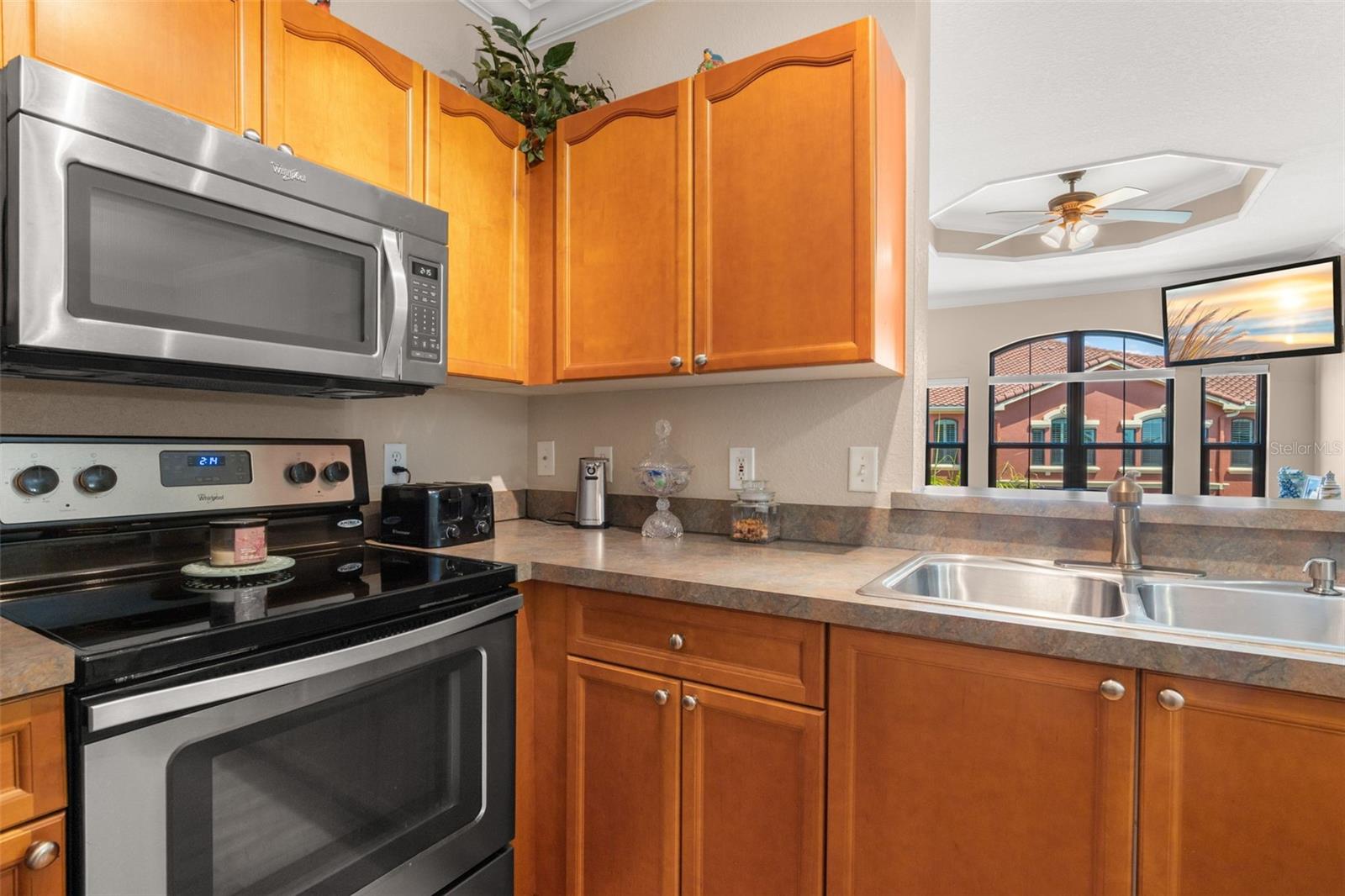 Warm wood cabinetry and stainless steel appliances create a functional kitchen with plenty of storage and prep space. The kitchen’s pass-through design keeps sightlines open to the living area, making the space feel connected and inviting.