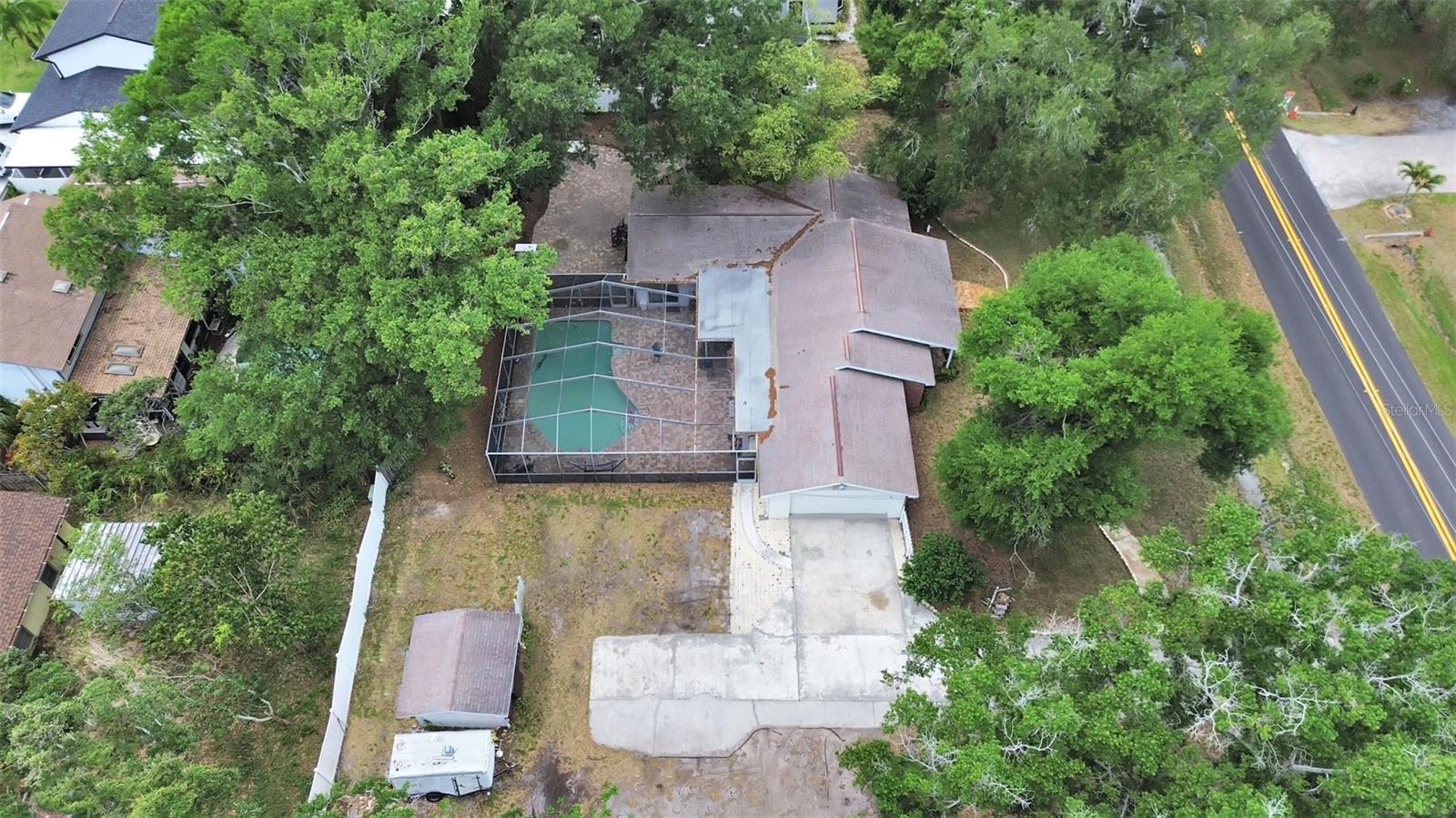 shows inground  pool with large screen enclosure, detached concrete block shed, lots of room for parking