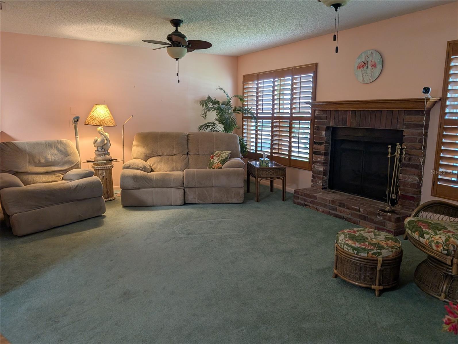 Carpeted Florida room has two windows framing the wood burning fireplace.