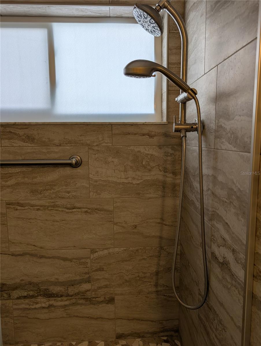 Other end of shower and close up view of tile which matches the flooring.