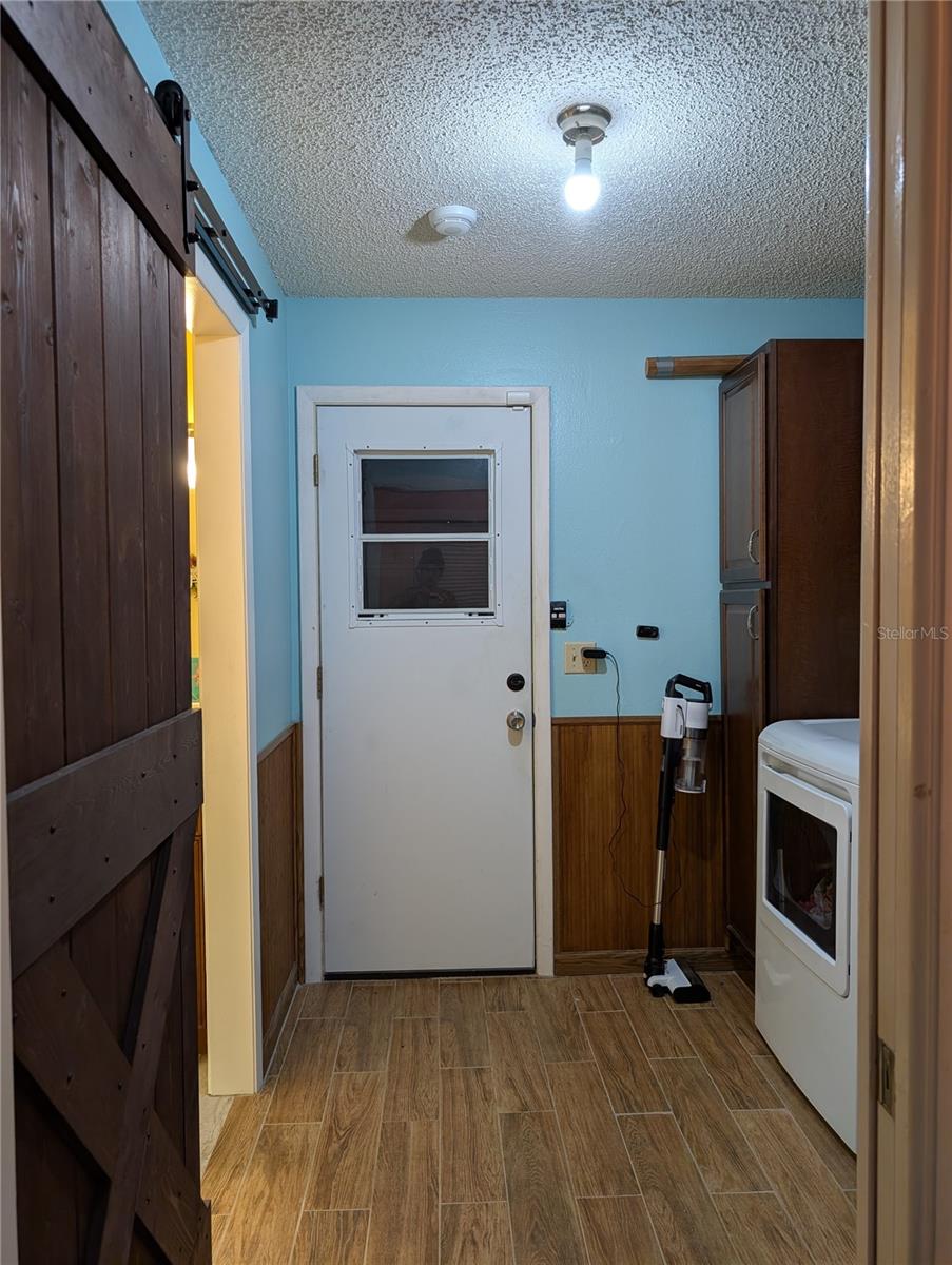 View from hallway to garage access door.  Barn door on left is to primary bathroom.