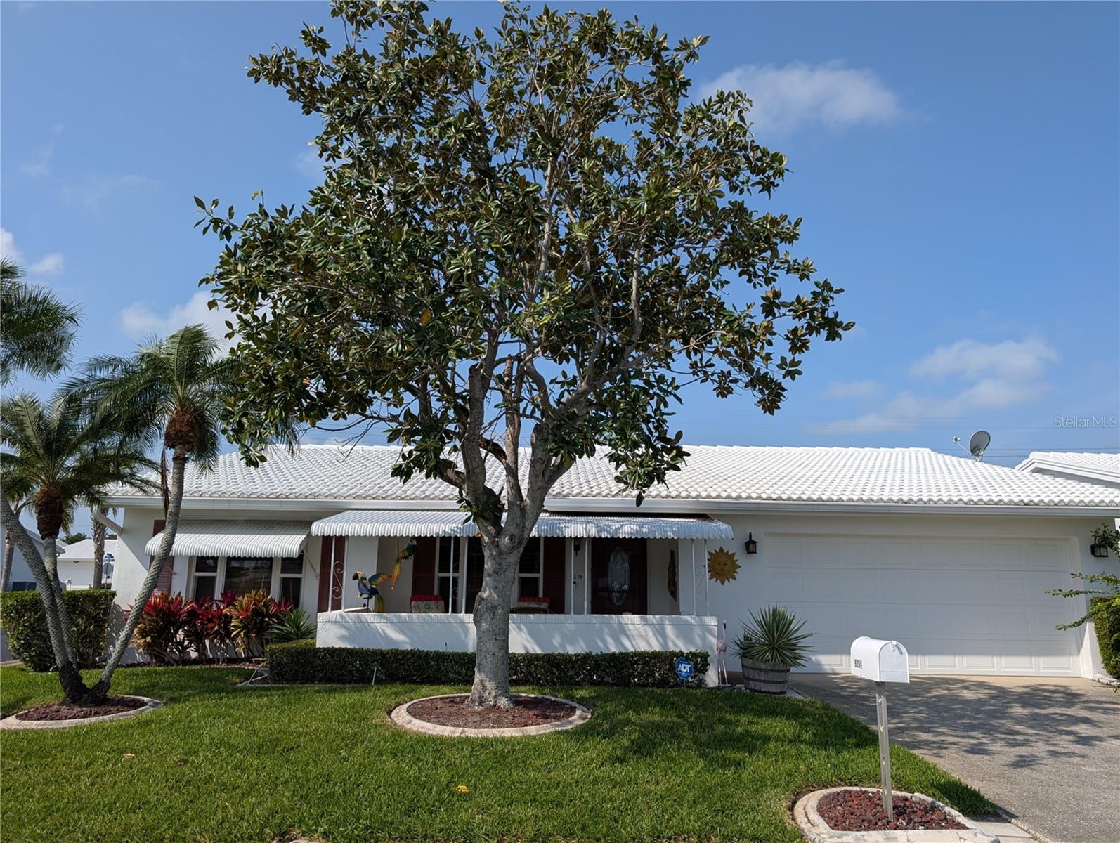 Landscaping is edged with cement curbing.  Exterior features also include gutters/downspouts, tile roof (2002), IMPACT windows (2009) and lawn/irrigation system (maintained by association). Oversized 2 car garage has updated electric panel w/whole house surge protector, Rheem hot water (2020), reinforced garage door, side man door and attic w/pull down ladder.