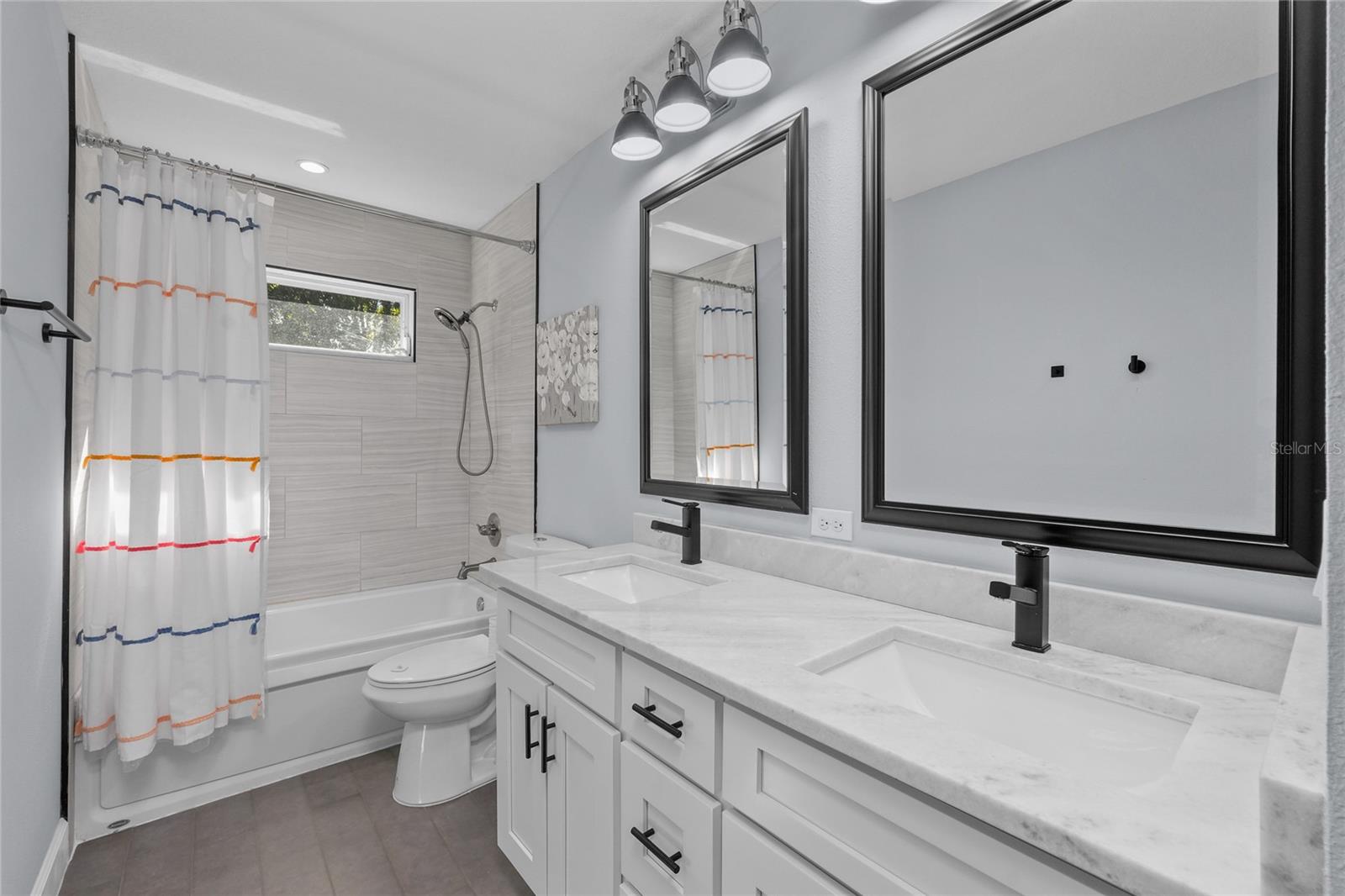 Bathroom 3 with dual sinks, marble countertops, floor to ceiling tile and a tub/shower combo