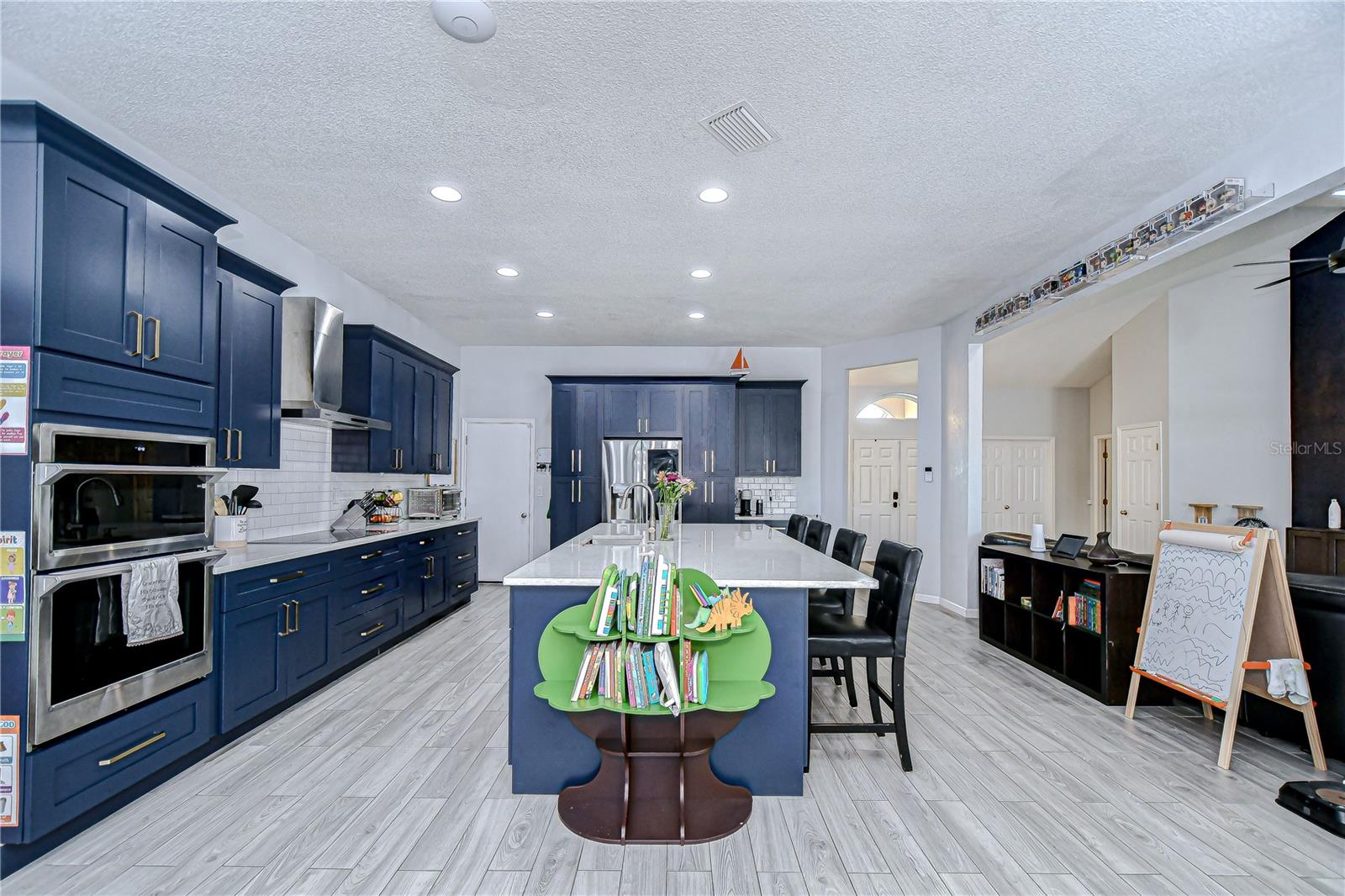 Spacious kitchen with cabinets topped with crown and stainless appliances.