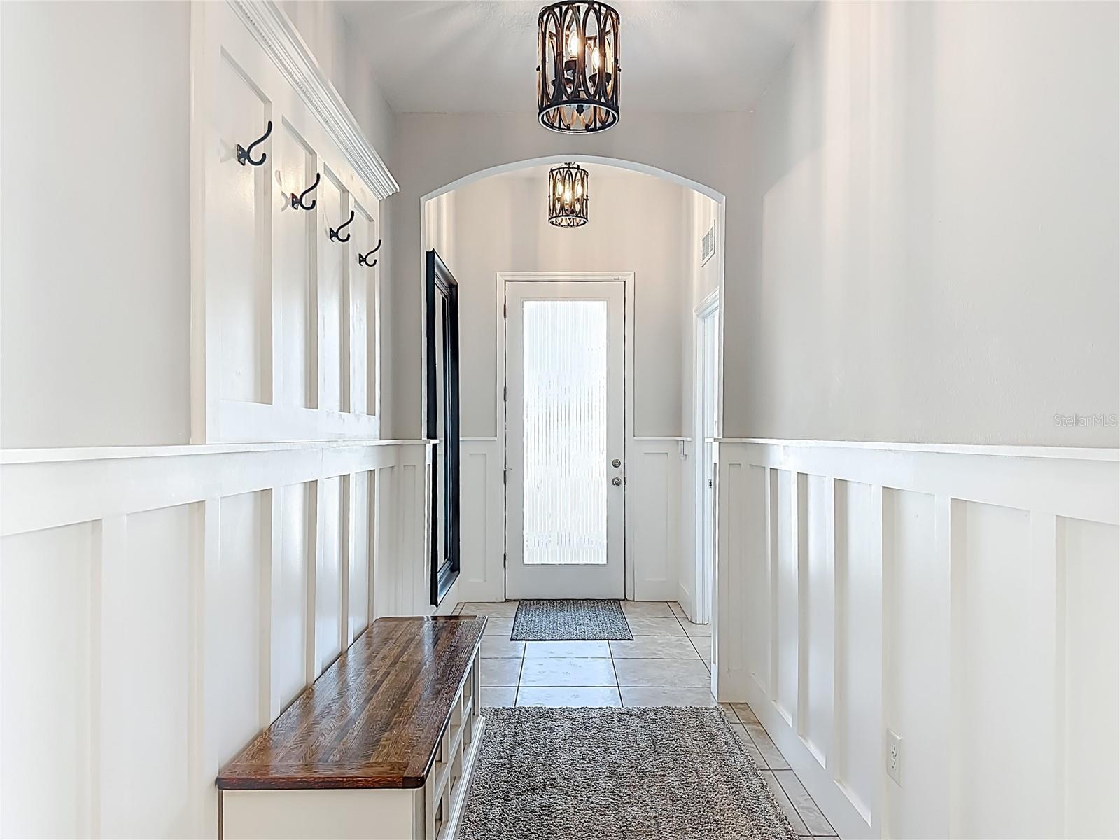 Bright, welcoming entry with custom wall design & stylish lighting