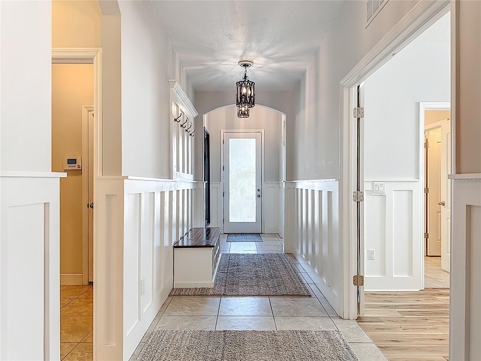 Bright, welcoming entry with custom wall design & stylish lighting