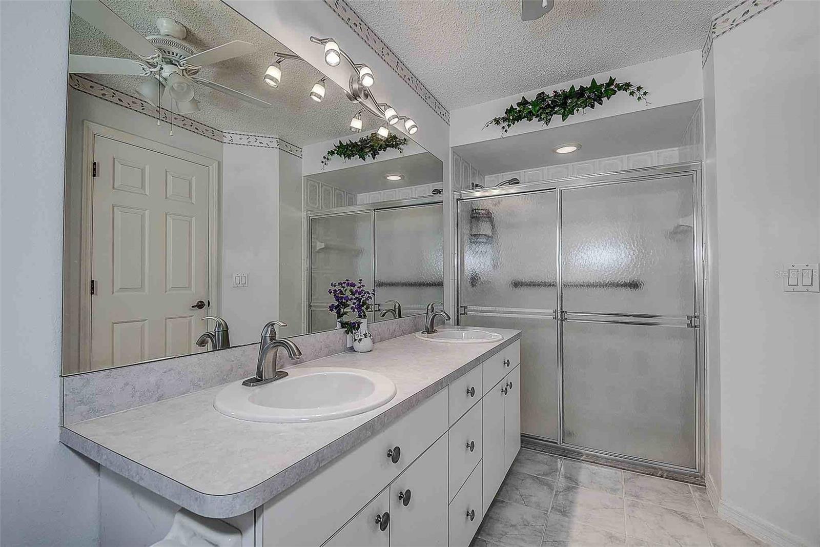 En suite with dual vanity, walk in shower and ceramic tile flooring.