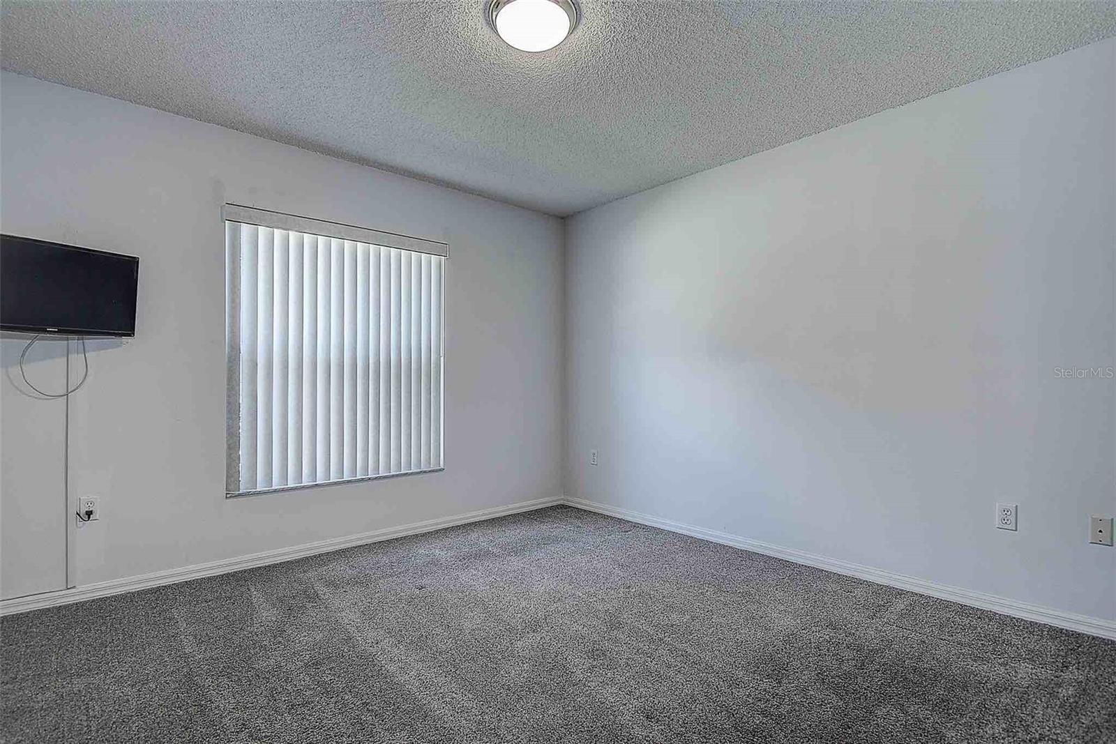 Secondary bedroom with picture window, ceiling light, built in closet and TV with mount conveys.
