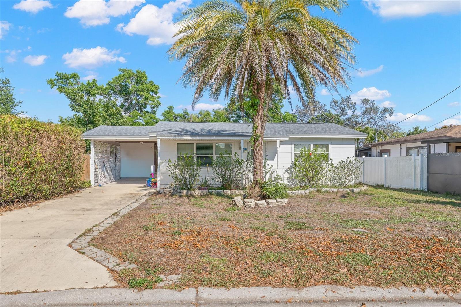 Charming 2-bedroom, 1-bath home with a welcoming front elevation, mature palm tree, and covered carport. The driveway offers ample parking, while the front yard provides a blank canvas for landscaping or outdoor living enhancements.