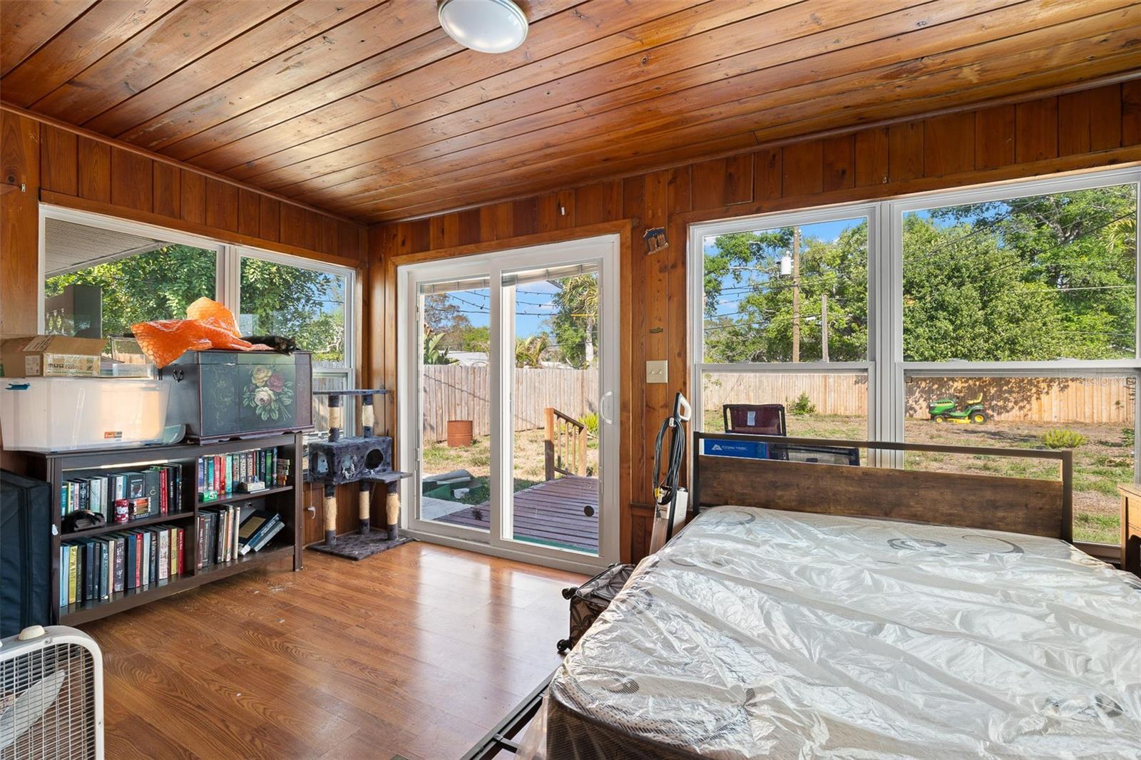 Bright Florida/bonus room with wood-paneled ceilings, multiple windows, and sliding glass doors leading to the backyard—ideal for additional living space, a home office, or a flexible retreat.