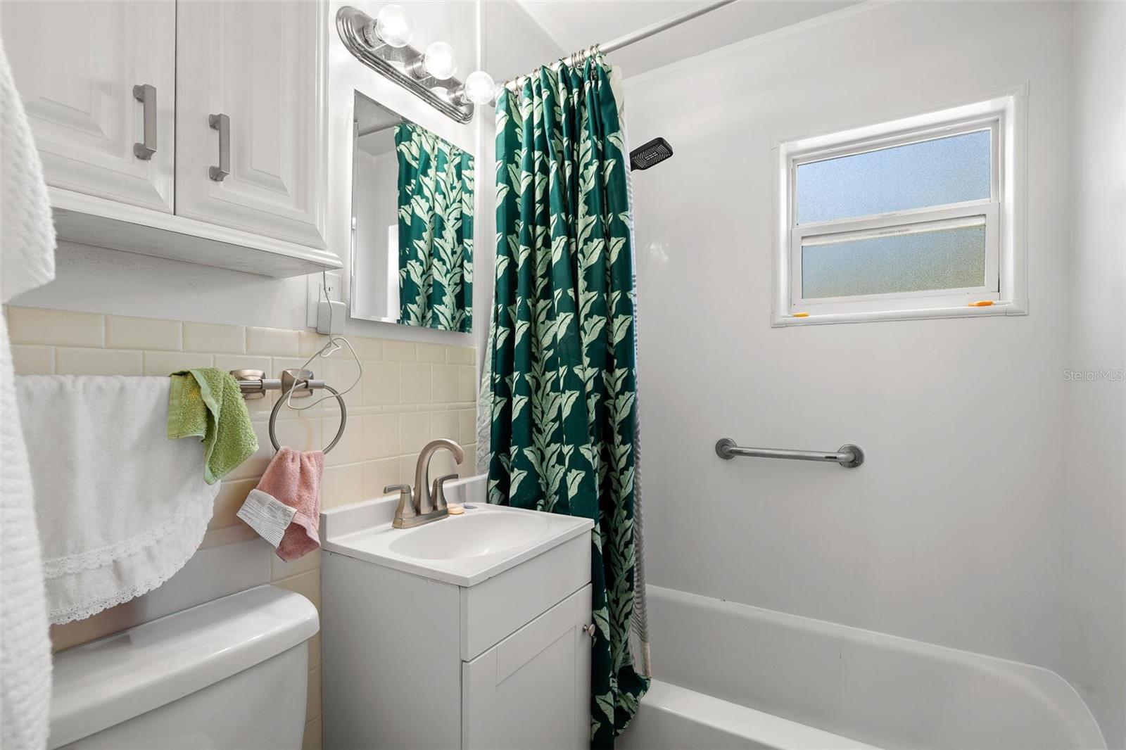 Well-maintained bathroom with a tub/shower combination, updated vanity, and a frosted window that brings in natural light while maintaining privacy.