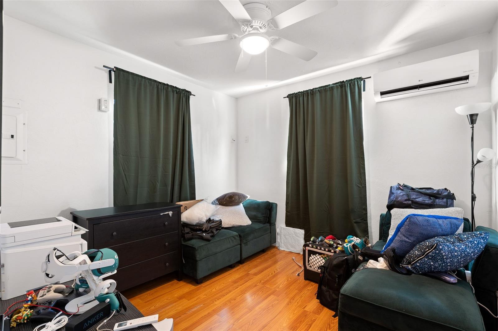 Versatile second bedroom with wood-look flooring, multiple windows, ceiling fan, mini-split a/c and a flexible layout ideal for a guest room, home office, or creative space.