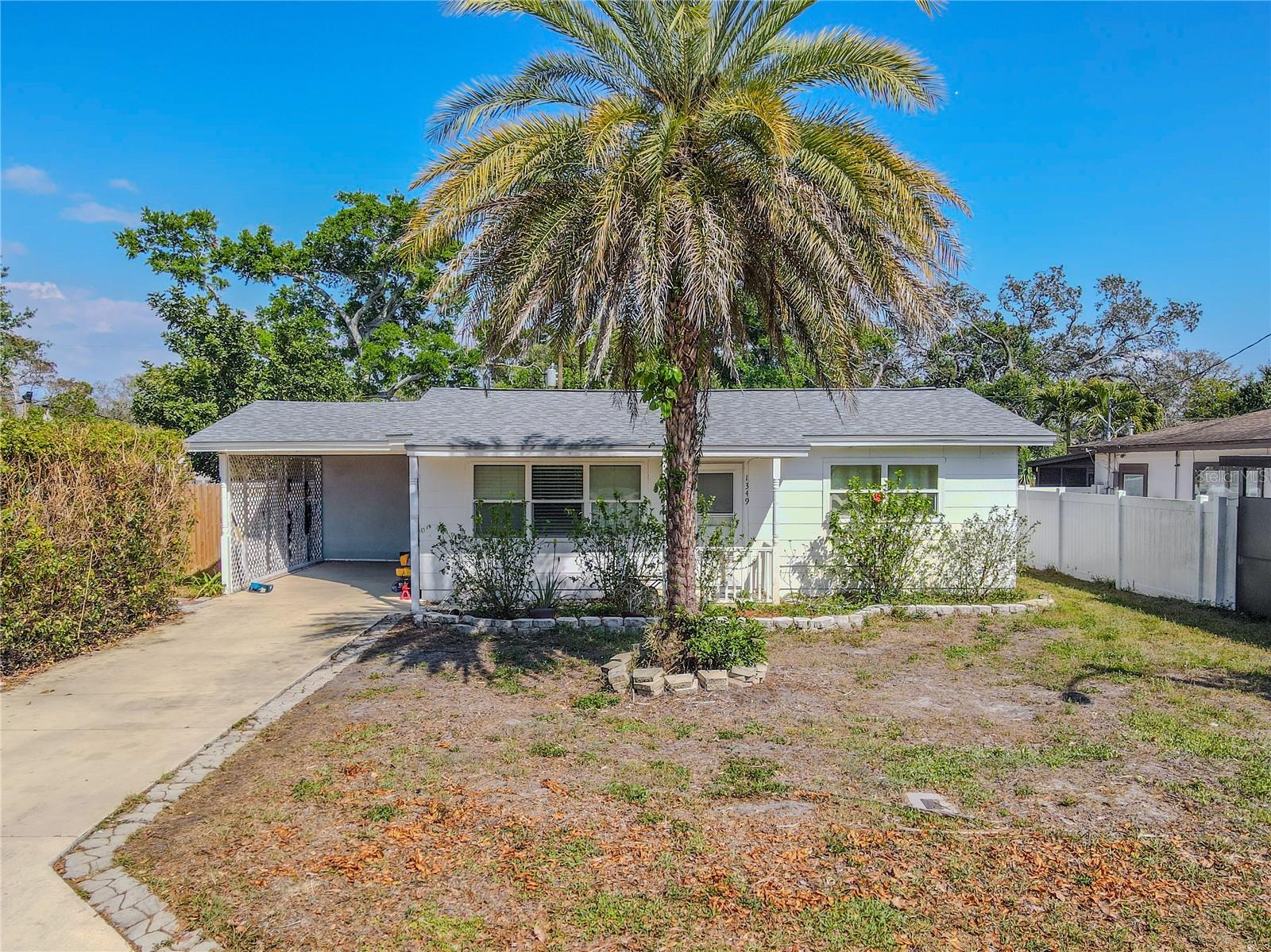 Charming 2-bedroom, 1-bath home with a welcoming front elevation, mature palm tree, and covered carport. The driveway offers ample parking, while the front yard provides a blank canvas for landscaping or outdoor living enhancements.