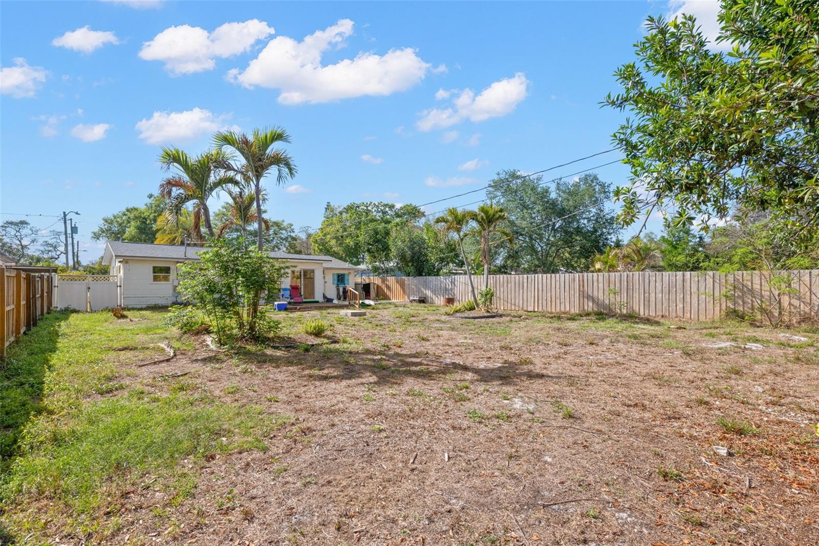Generous fenced backyard with a wood deck and plenty of open space, offering endless potential for outdoor living, gardening, or entertaining.