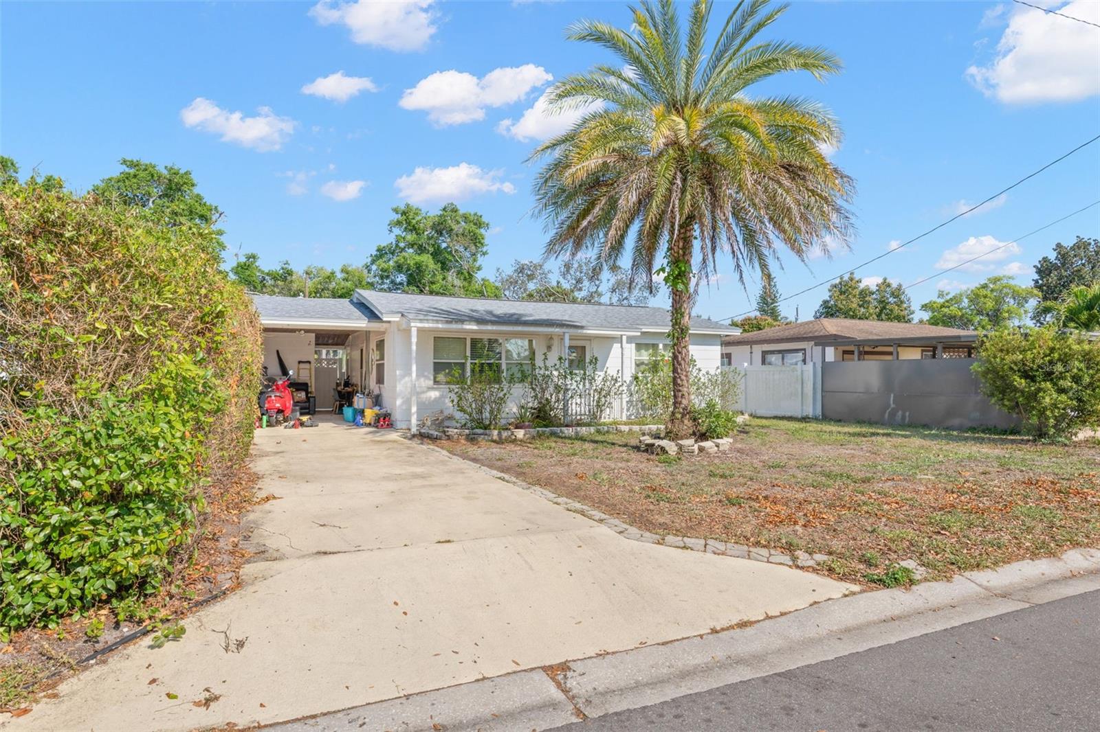 The driveway leads to a covered carport with additional storage and workspace potential—ideal for everyday convenience, hobbies, or protected parking.