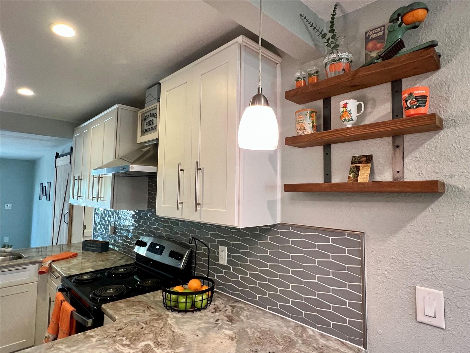 Granite countertops, plenty of wood, Shaker style cabinetry, whimsical hexagonal blacksplash and open shelving for all of your favorite mementos makes for a modern kitchen with details of its Mid Century Modern past.