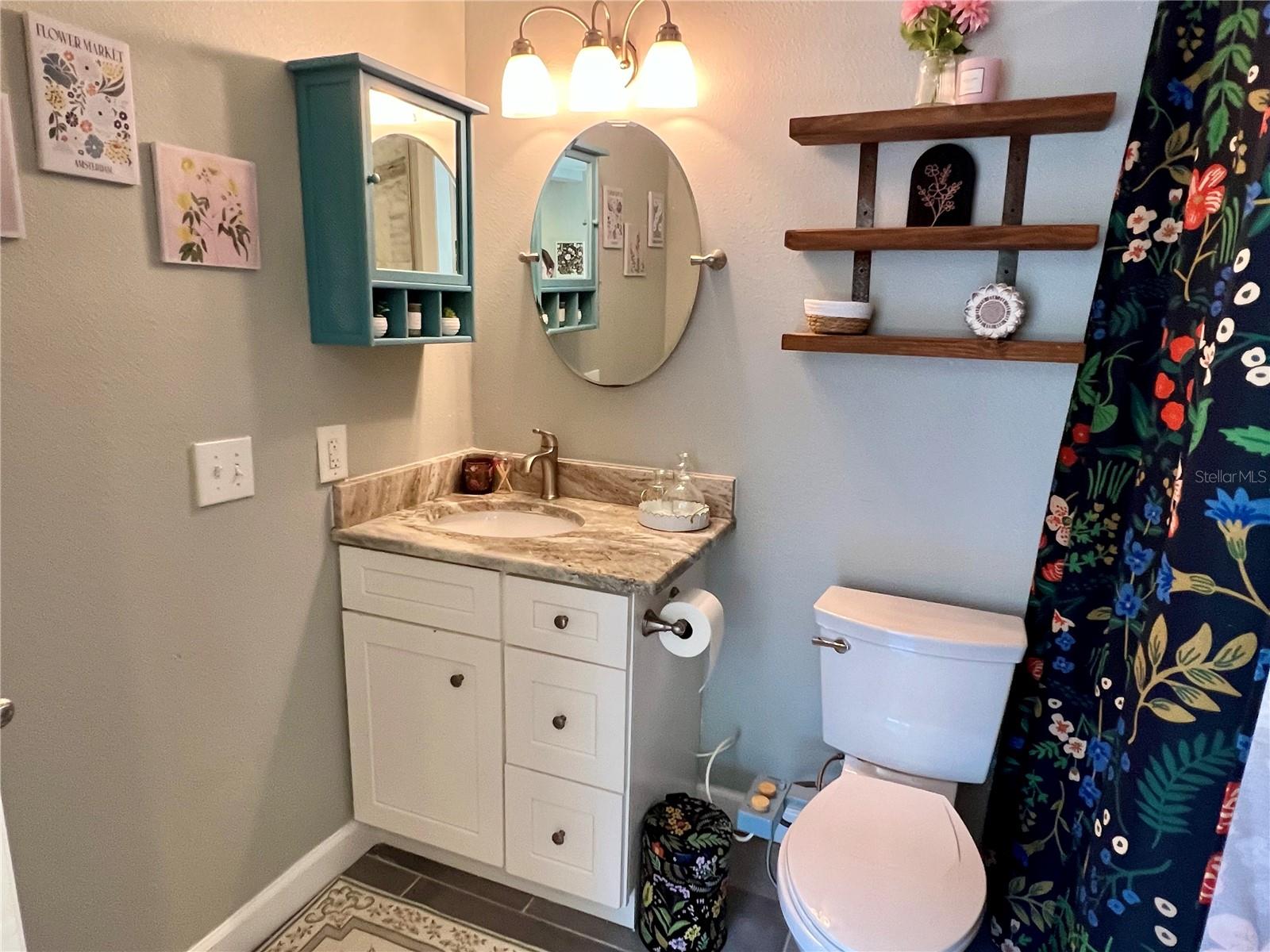 A full size bathroom with granite countertops, open shelving and more storage is tastefully tucked away behind a beautiful barn door.