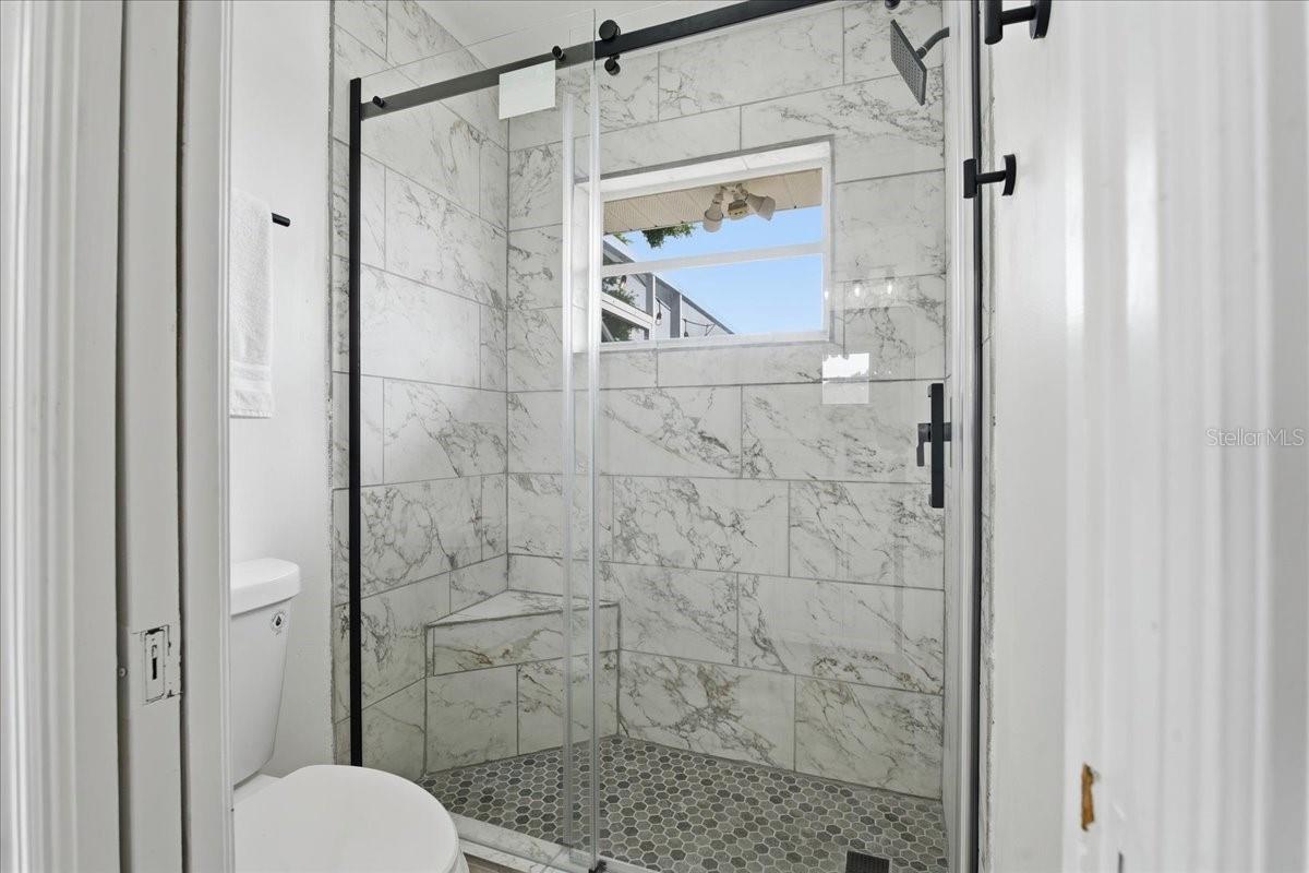 WALK IN SHOWER IN THE PRIMARY BATHROOM WITH SLIDING GLASS DOORS