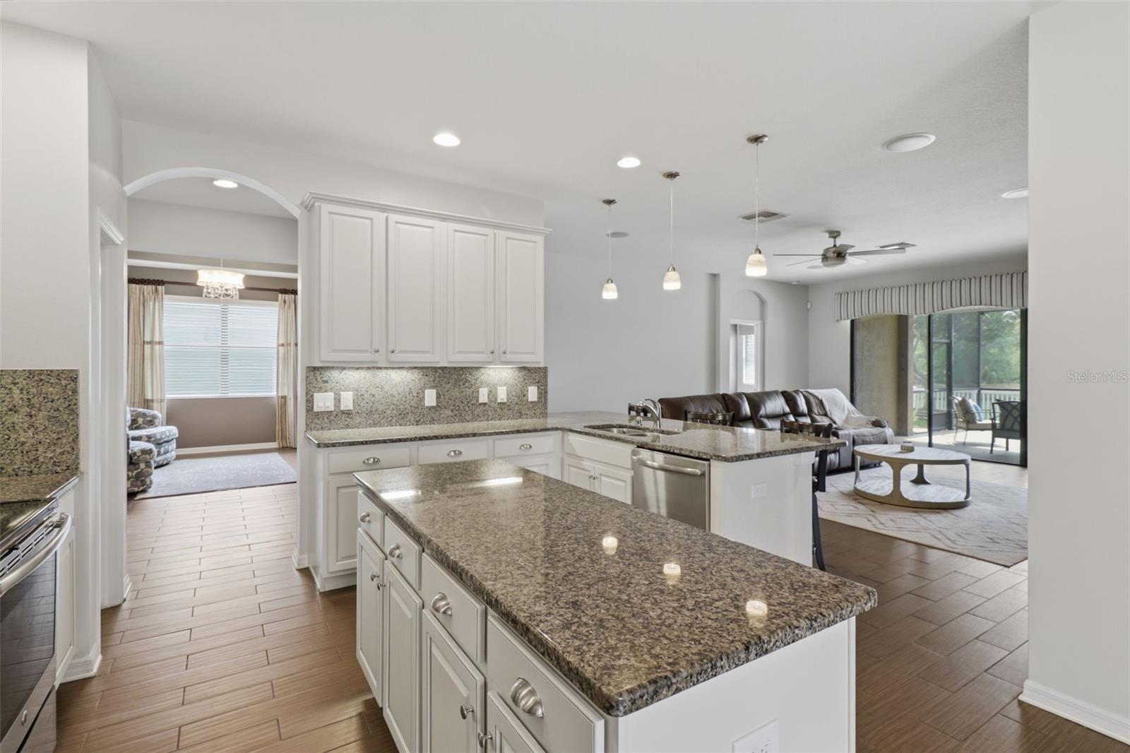 Spacious chef’s kitchen featuring granite countertops, a large center prep island, abundant cabinetry, and an open layout ideal for both everyday living and entertaining.
