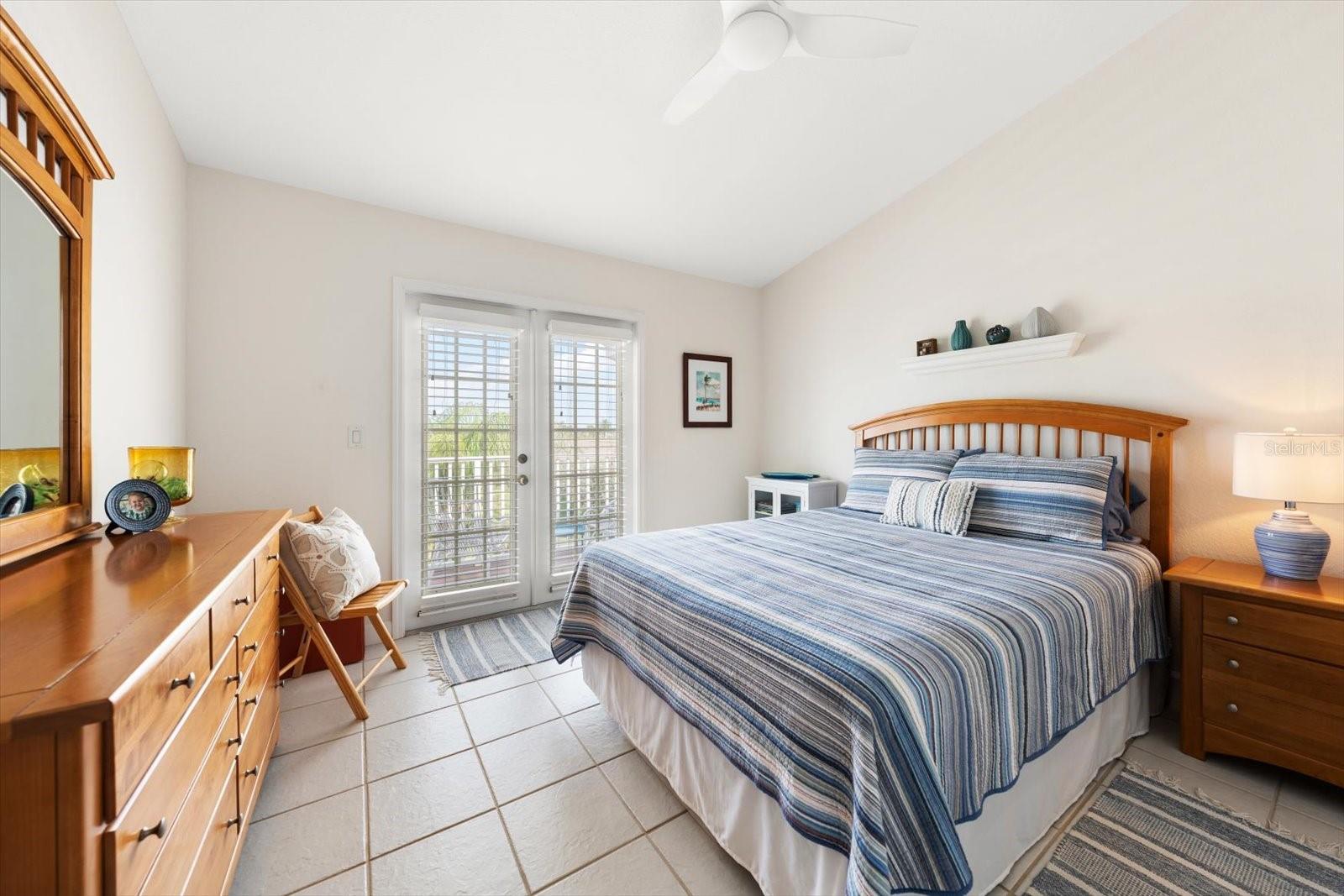Beautifully illuminated guest bedroom with tall ceilings and access to a shared balcony.