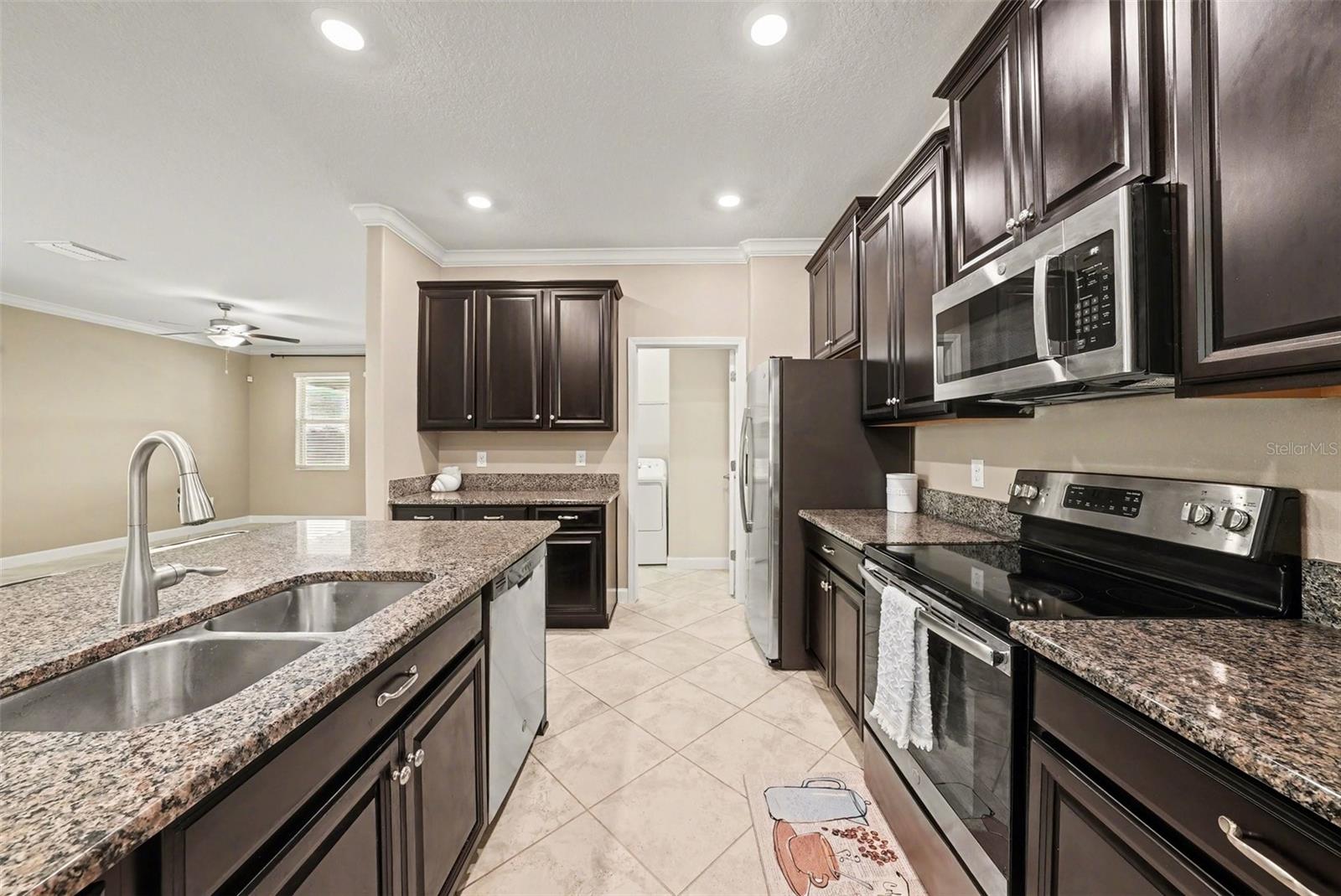 The spacious Kitchen features pull out shelves and leads to the laundry room and back door to the Primary Suite.