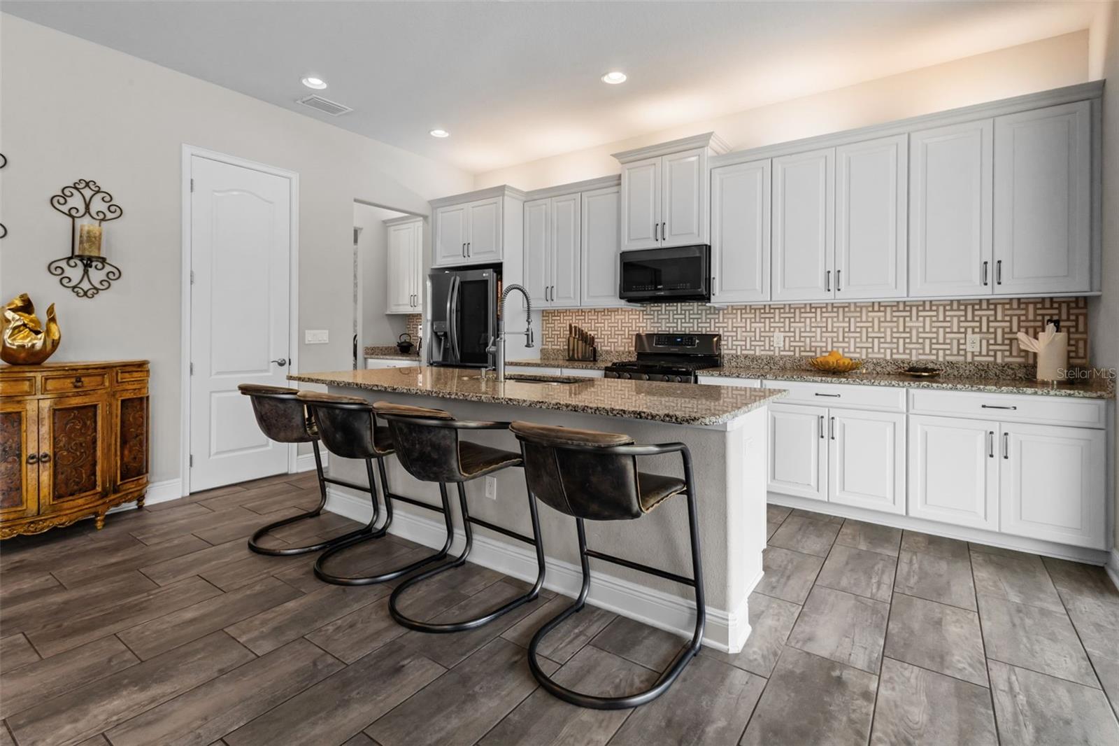 Upgraded kitchen with custom cabinetry, gas range, and large center island.