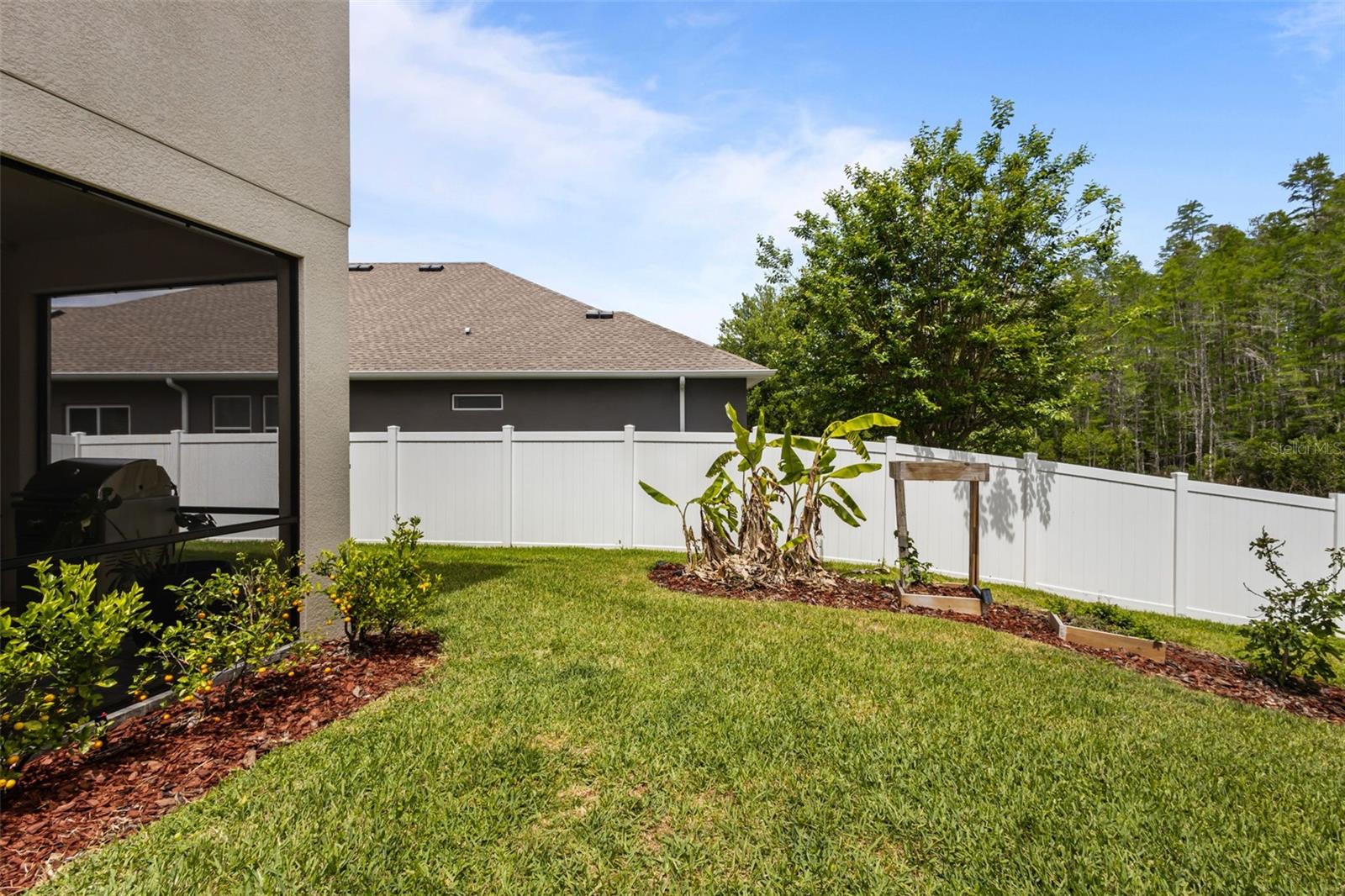 Immaculate landscaping with fruit trees and private conservation backdrop.