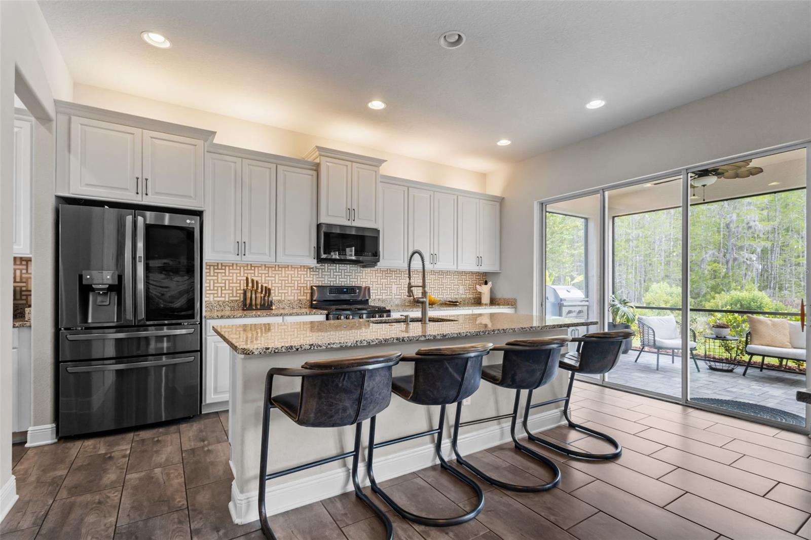 Upgraded kitchen with custom cabinetry, gas range, and large center island.