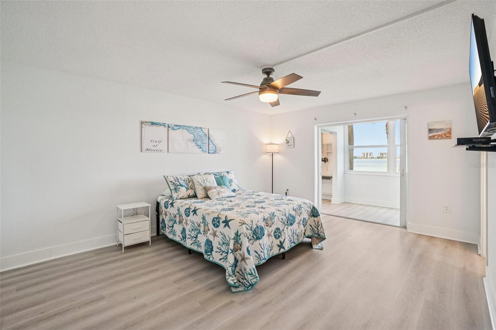 Primary Bedroom – This generously sized primary bedroom features light luxury vinyl plank flooring, a modern ceiling fan, and a walk-in closet — all dressed in a soothing coastal palette that invites relaxation from the moment you walk in.