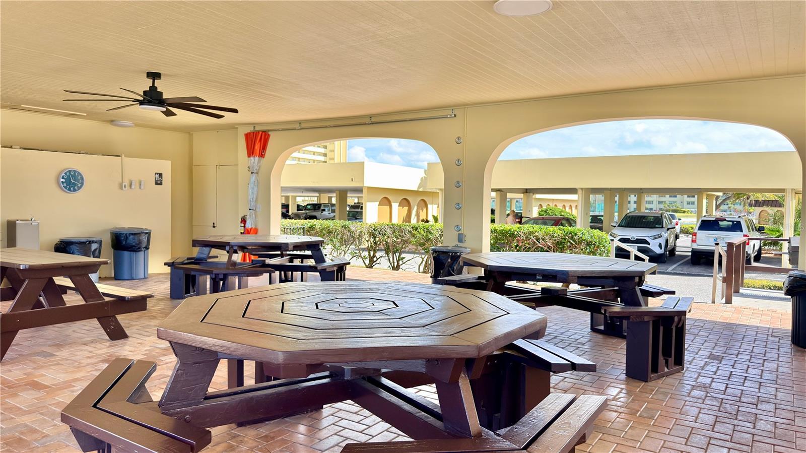 Community Pavilion & Gathering Area – This spacious covered pavilion offers ample seating with large octagonal picnic tables, a ceiling fan for comfort, and open-air arched openings — ideal for community gatherings, al fresco dining, or simply enjoying the shade on a sunny Florida afternoon.