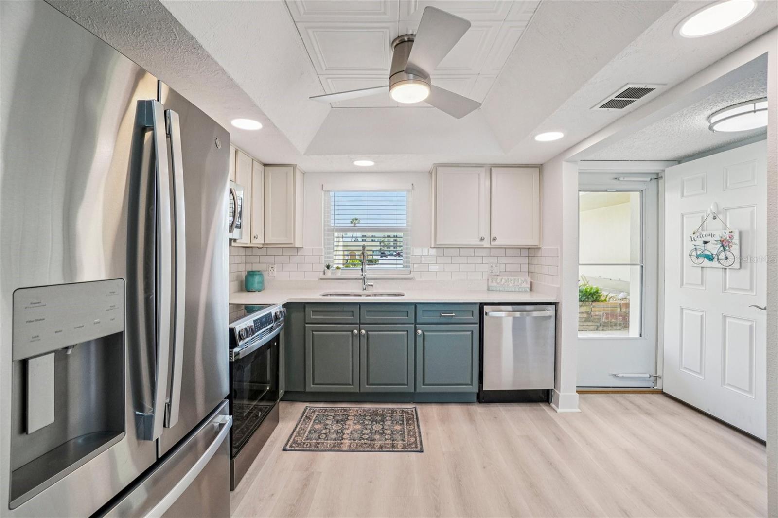 Kitchen with Entry View – This well-appointed kitchen offers a full stainless steel appliance package, ample two-tone cabinetry, quartz countertops, and a recessed-lit coffered ceiling, with a convenient direct view to the front entry door — adding both functionality and easy flow to the layout.