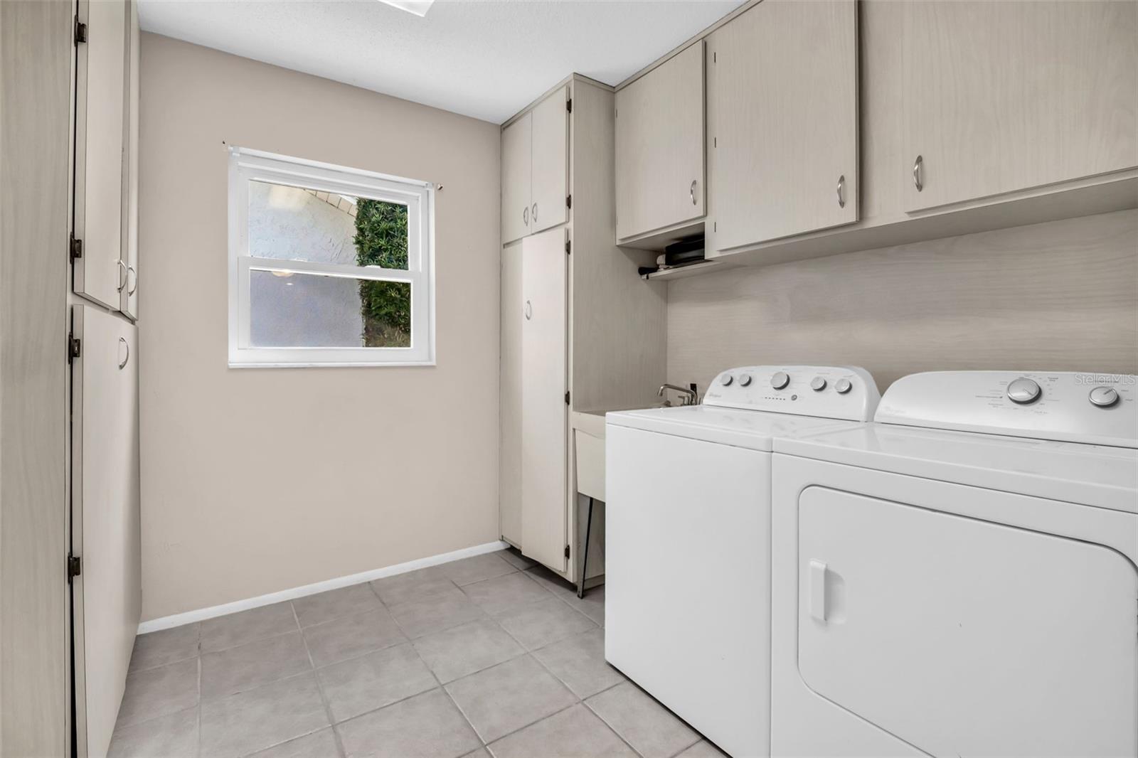 Gracious indoor laundry plus utility sink with abundant cabinetry for storage~