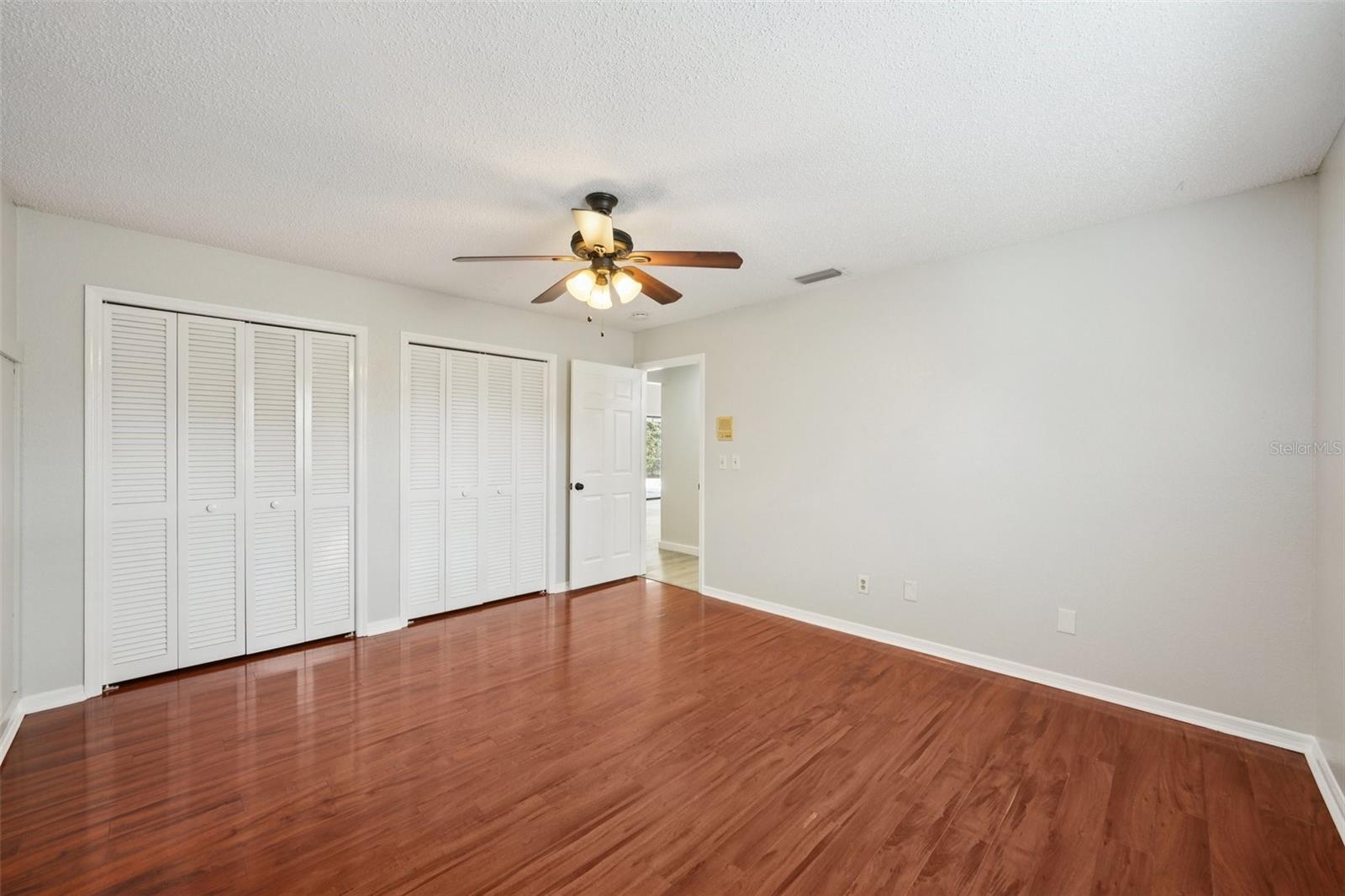 Second bedroom with laminate flooring, wall of closets and decorative box molding accent wall.