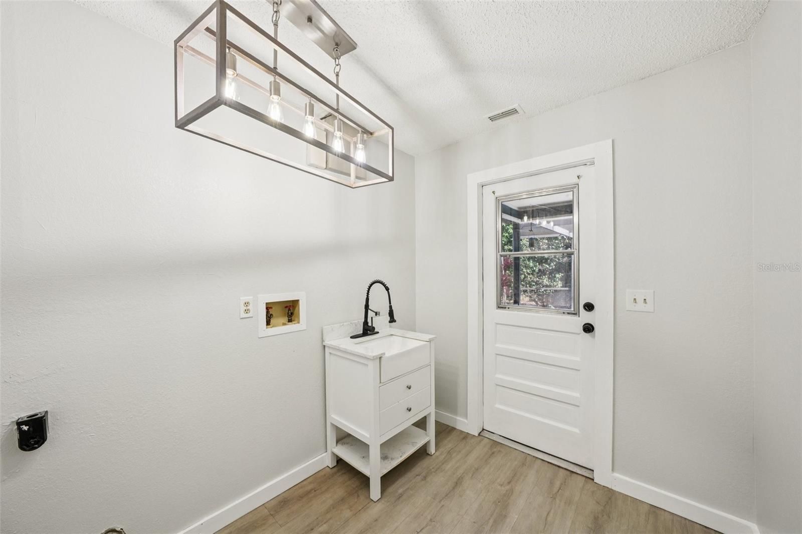 Utility rooA utility room off the kitchen provides washer and dryer hookups, a sink with vanity storage, and direct access to the pool and patio area. m