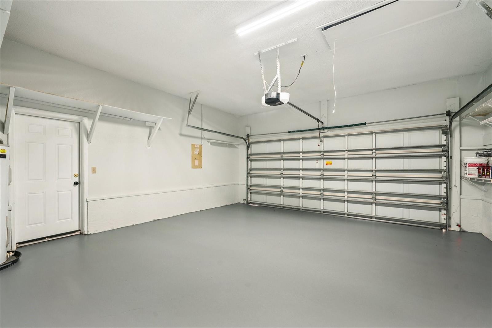 Neat and clean garage with newer flooring and added shelving.