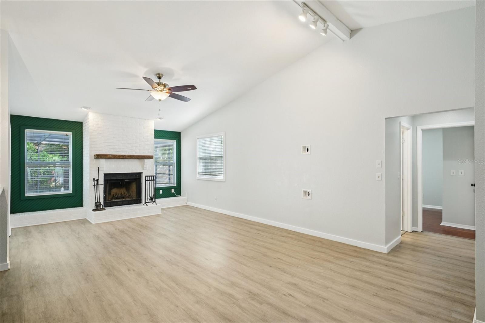 The family room features vaulted ceilings, a wood-burning fireplace with hearth and mantle, and an energy-efficient solar tube skylight that fills the space with natural, diffused light. Sliding glass doors lead to the covered patio and screened-in pool area, extending the living space outdoors.