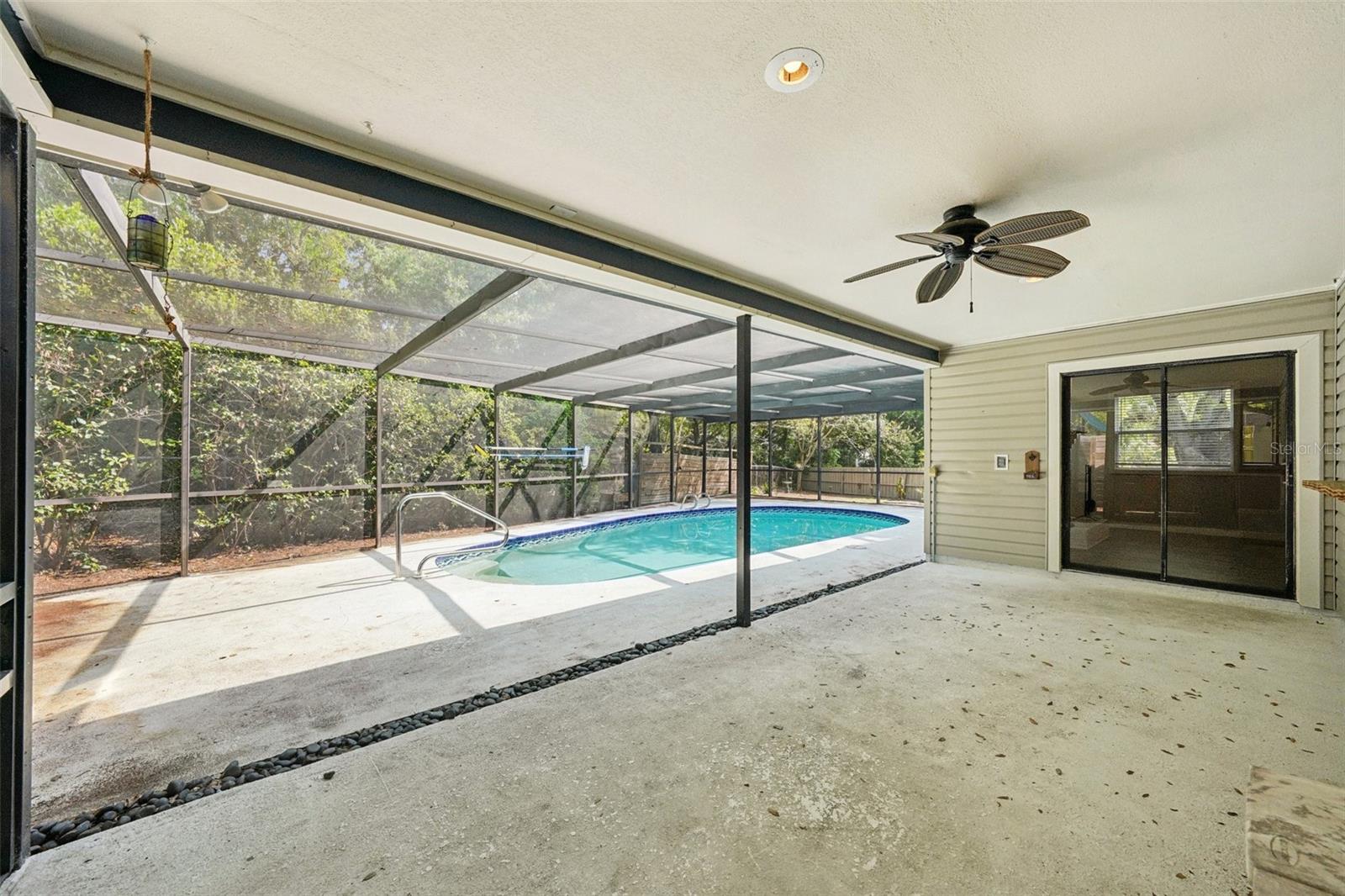 The screened-in pool area includes a covered area to sit and relax with a sparkling Pebble Tec pool to cool off in and enjoy the Florida weather.