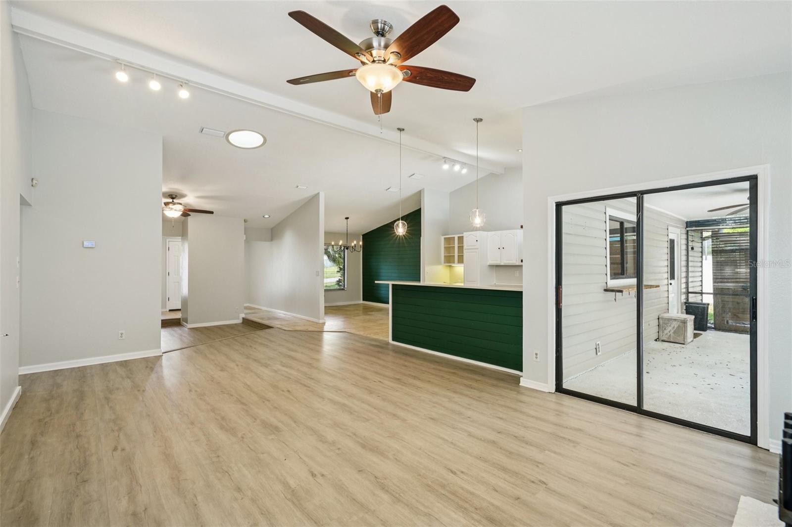 The family room features vaulted ceilings, a wood-burning fireplace with hearth and mantle, and an energy-efficient solar tube skylight that fills the space with natural, diffused light. Sliding glass doors lead to the covered patio and screened-in pool area, extending the living space outdoors.