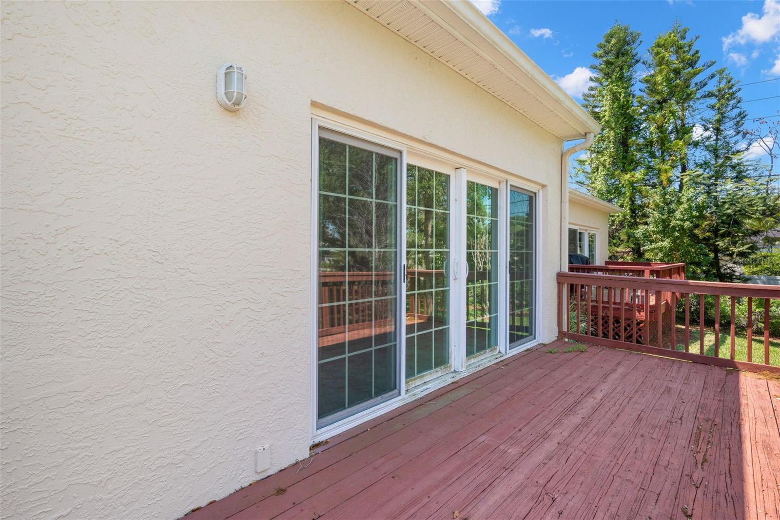 Sliding glass doors extend across the rear of the main living area, creating a seamless connection to the expansive deck.