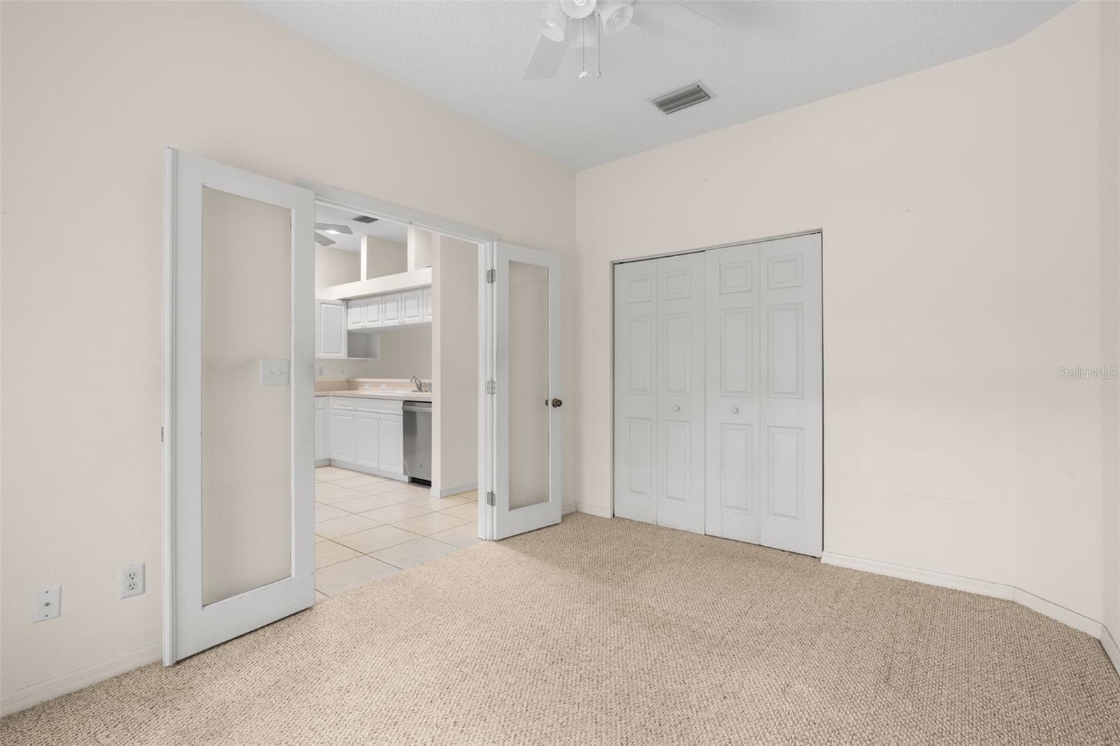 Third bedroom featuring French doors that open to the main living area, along with a built-in closet for convenient storage.