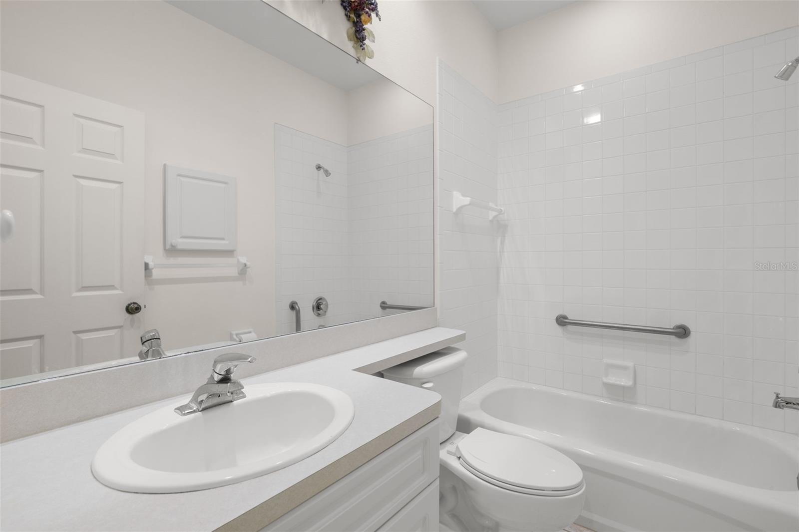 Bathroom 2 with a tub and shower combination, tile surround, and a single-sink vanity, offering a clean and functional layout.
