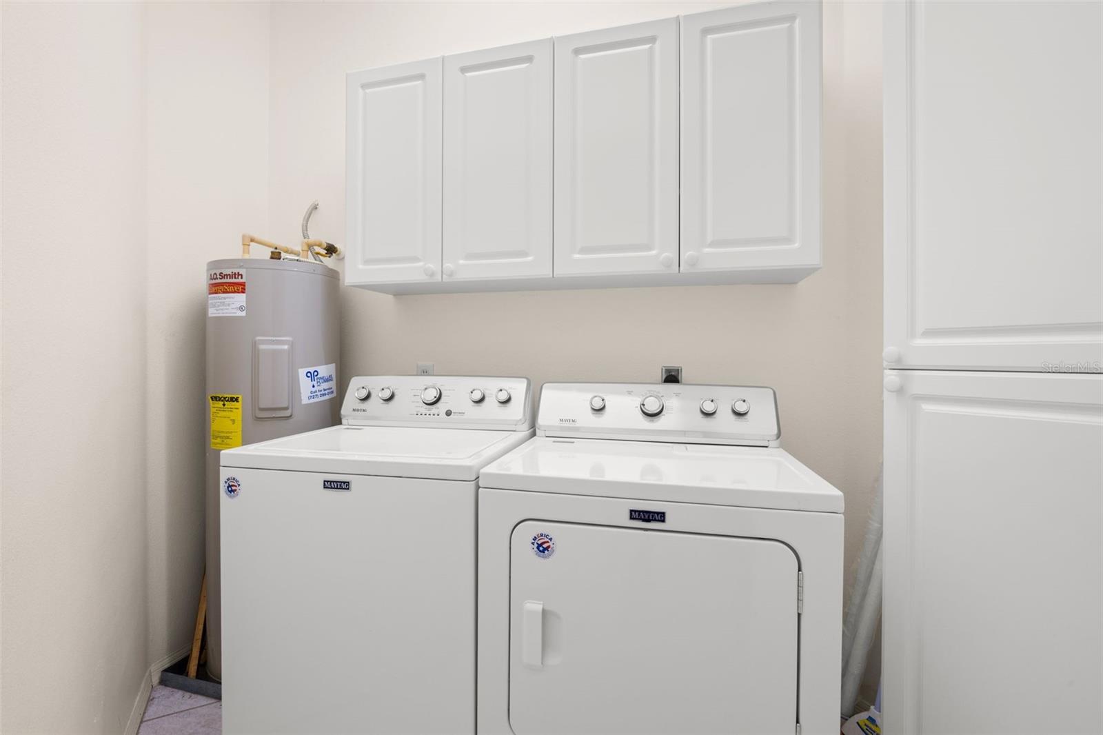 Separate laundry room featuring a full-size washer and dryer, overhead cabinetry, and built-in storage for added convenience.