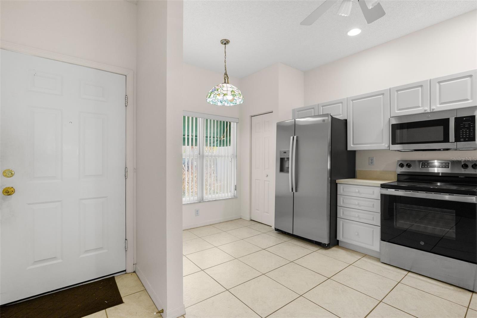 Entry way with kitchen to the left. The kitchen features a ceiling fan with light kit, stainless steel appliances and a breakfast nook.